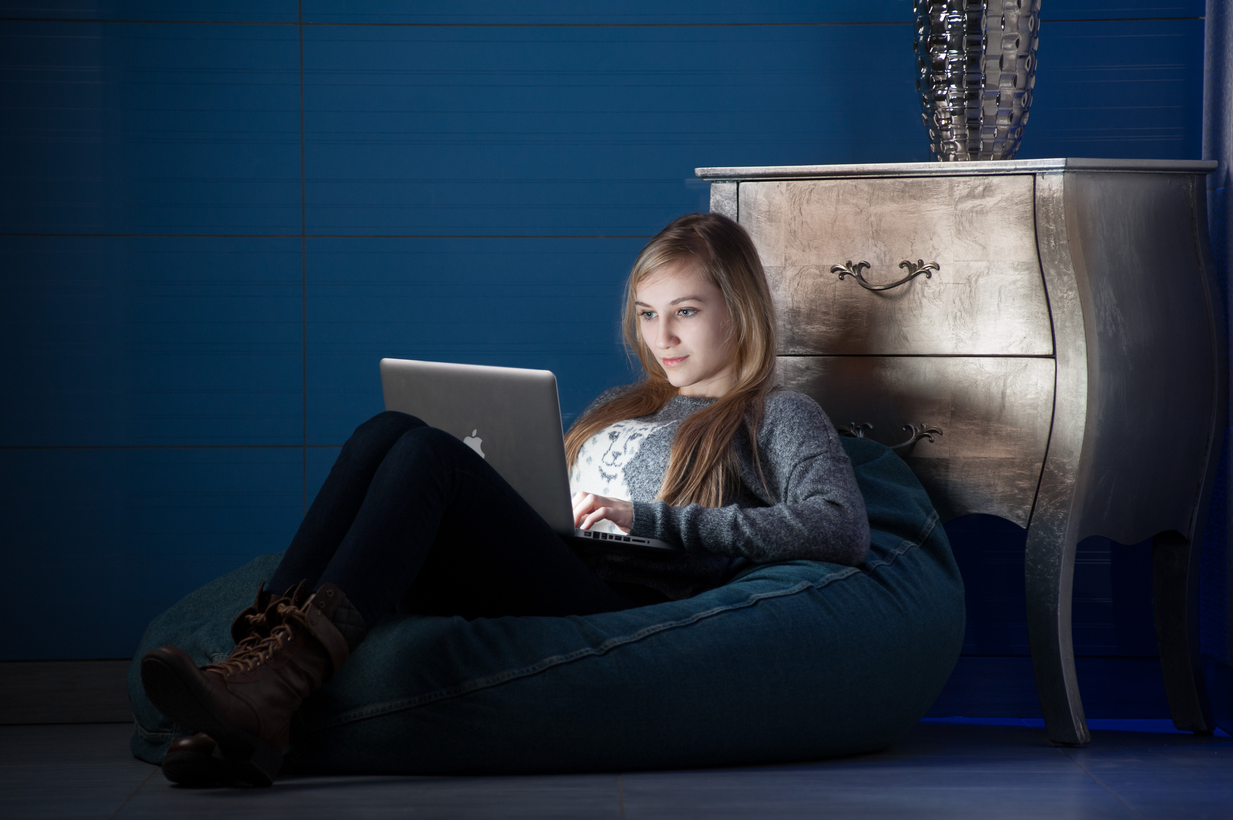 A student sits in front of a computer in a floor chair.