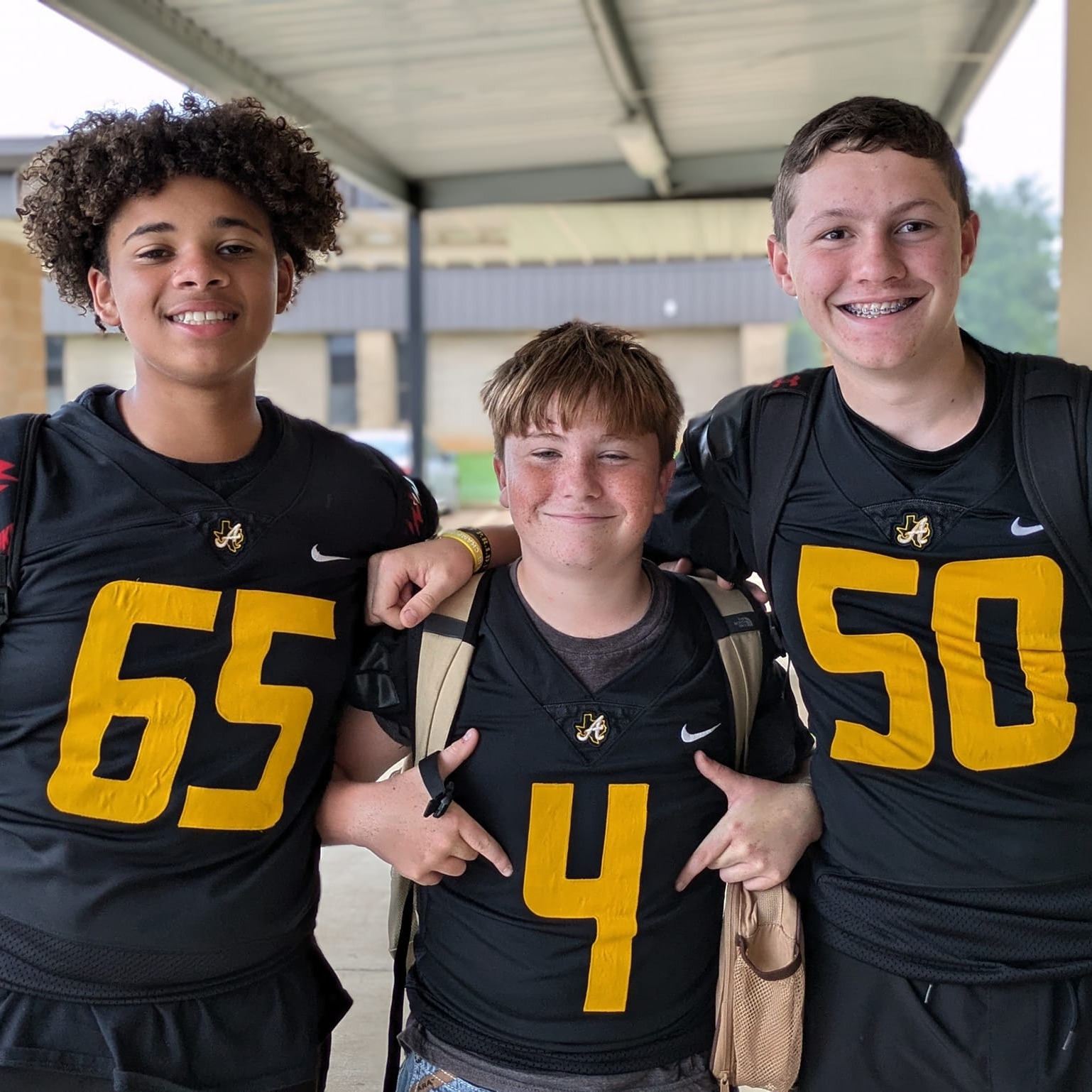 three middle school football players smiling