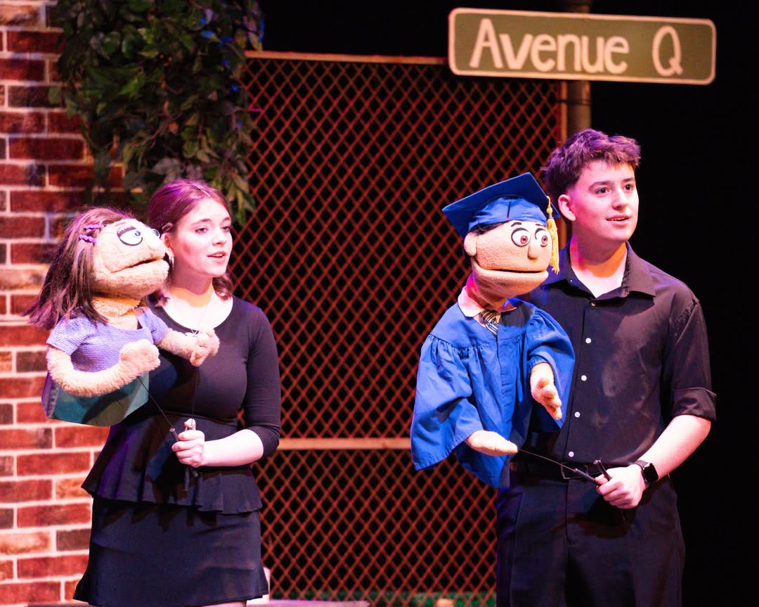 Theater production with female and male cast members holding puppets