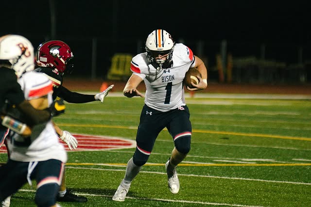 BGHS Football player wearing jersey #1 running with the ball on the football field during a game