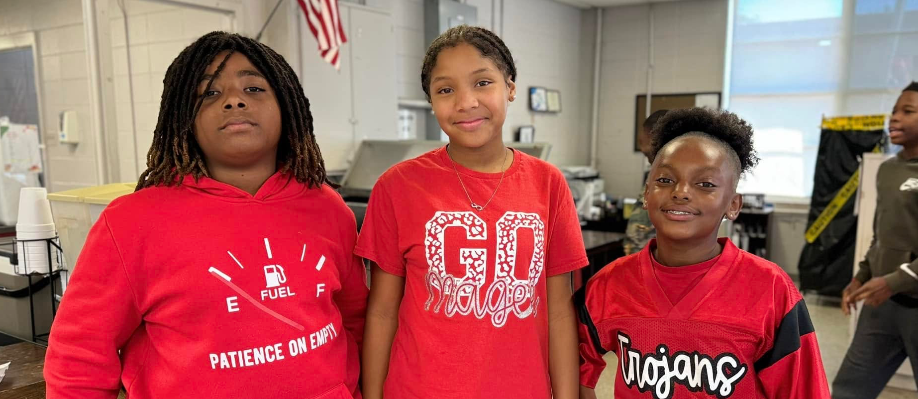 Three students posing for a photo in Magee Middle School's cafeteria for Red Ribbon Week. 