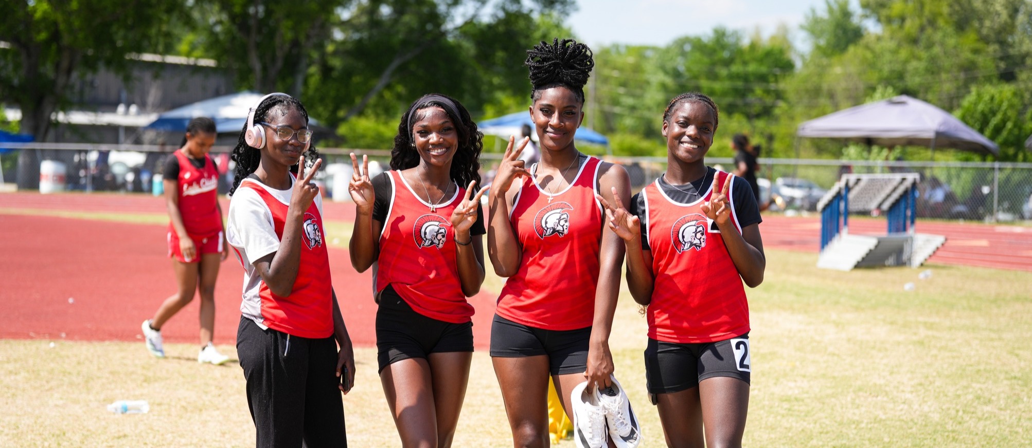 Four members of the Magee High School Girls track team pose for a photo at a track meet.