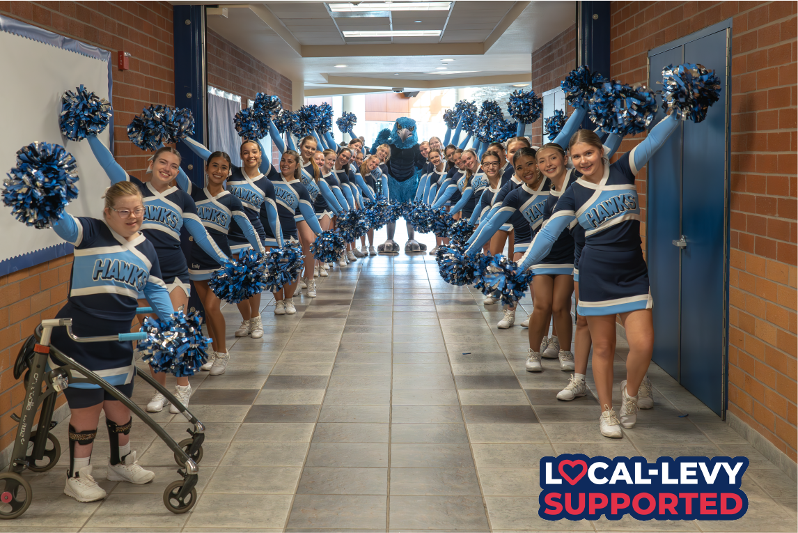 Group of cheer athletes pose with pom poms indoors