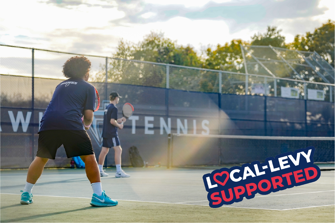 Boys tennis athletes stand with rackets in hand on the court