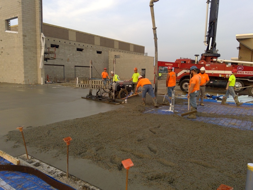 Photo of the workers pouring concrete in the new academic wing.