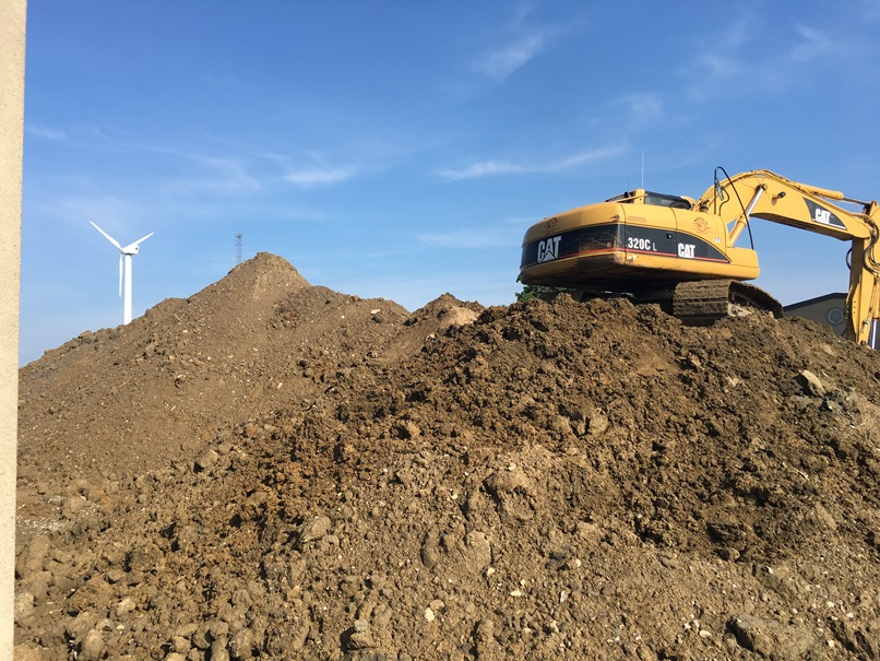 Photo of the mound of dirt next to the high school building is being moved to the back of the elementary school.