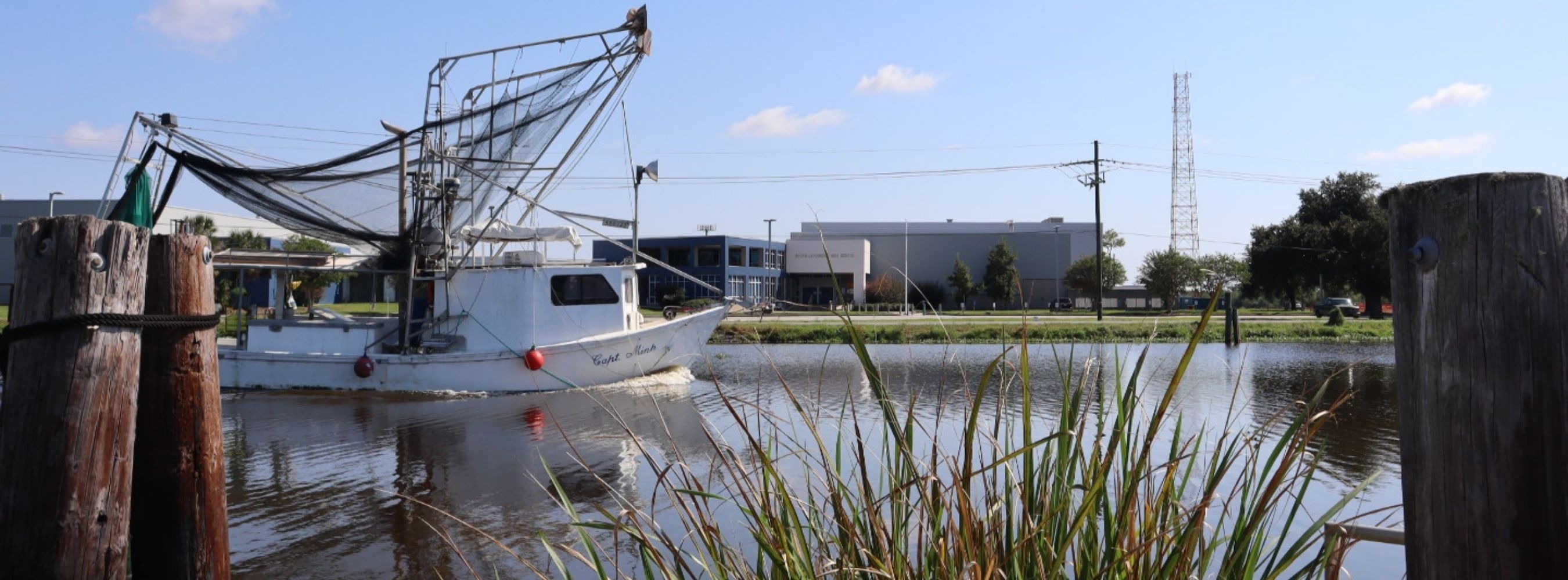 A picture of the school building South Lafourche High school with a trawl boat and bayou in front of it