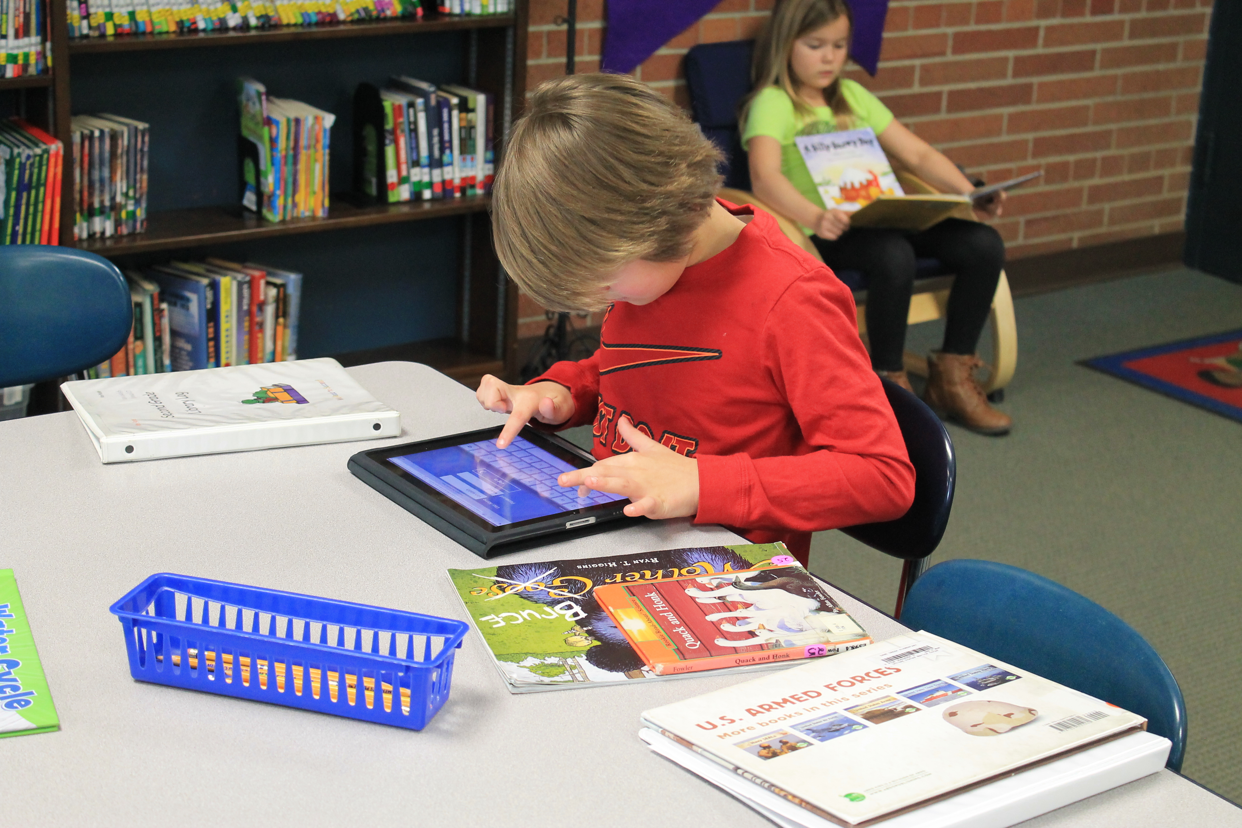 A small boy playing with an educational I-Pad in the library's school.