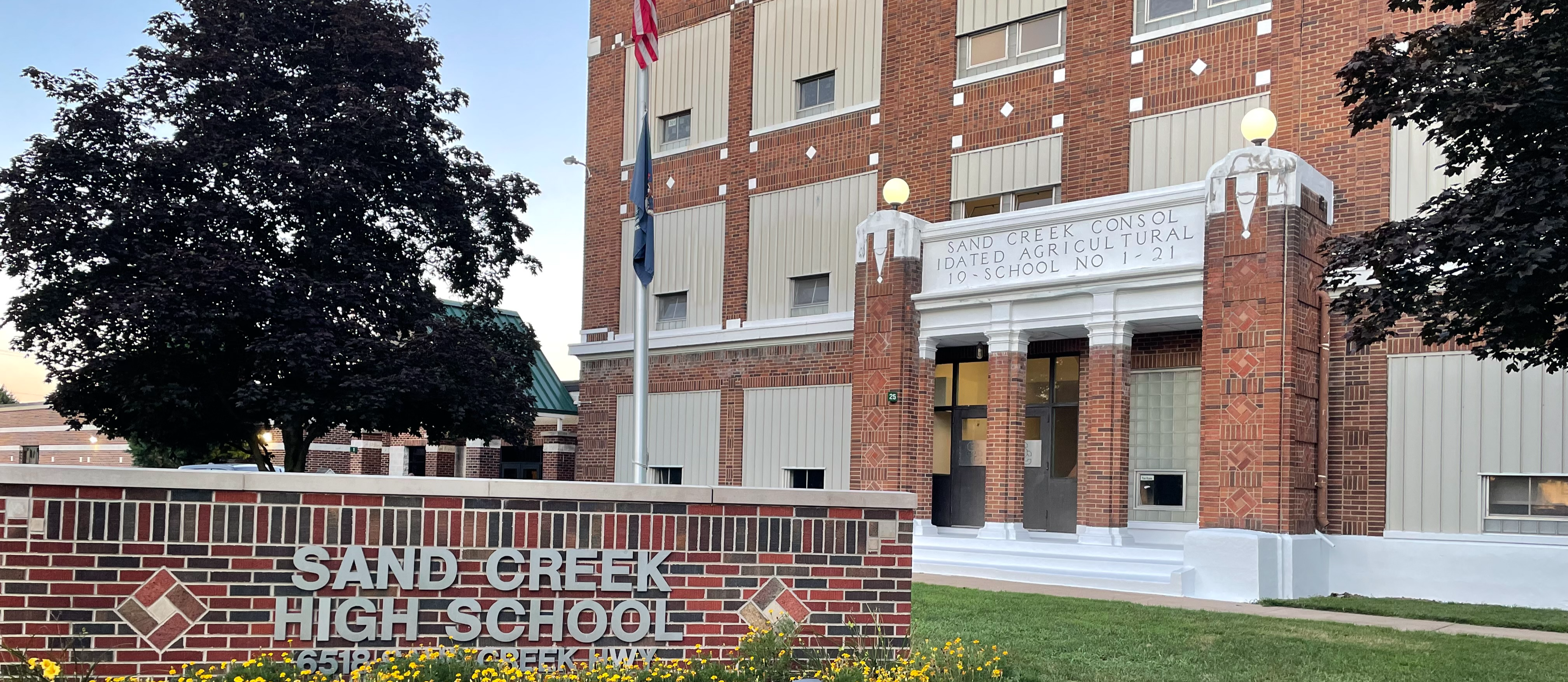 picture of the Sand Creek High School sign on the front lawn with the entrance in the background