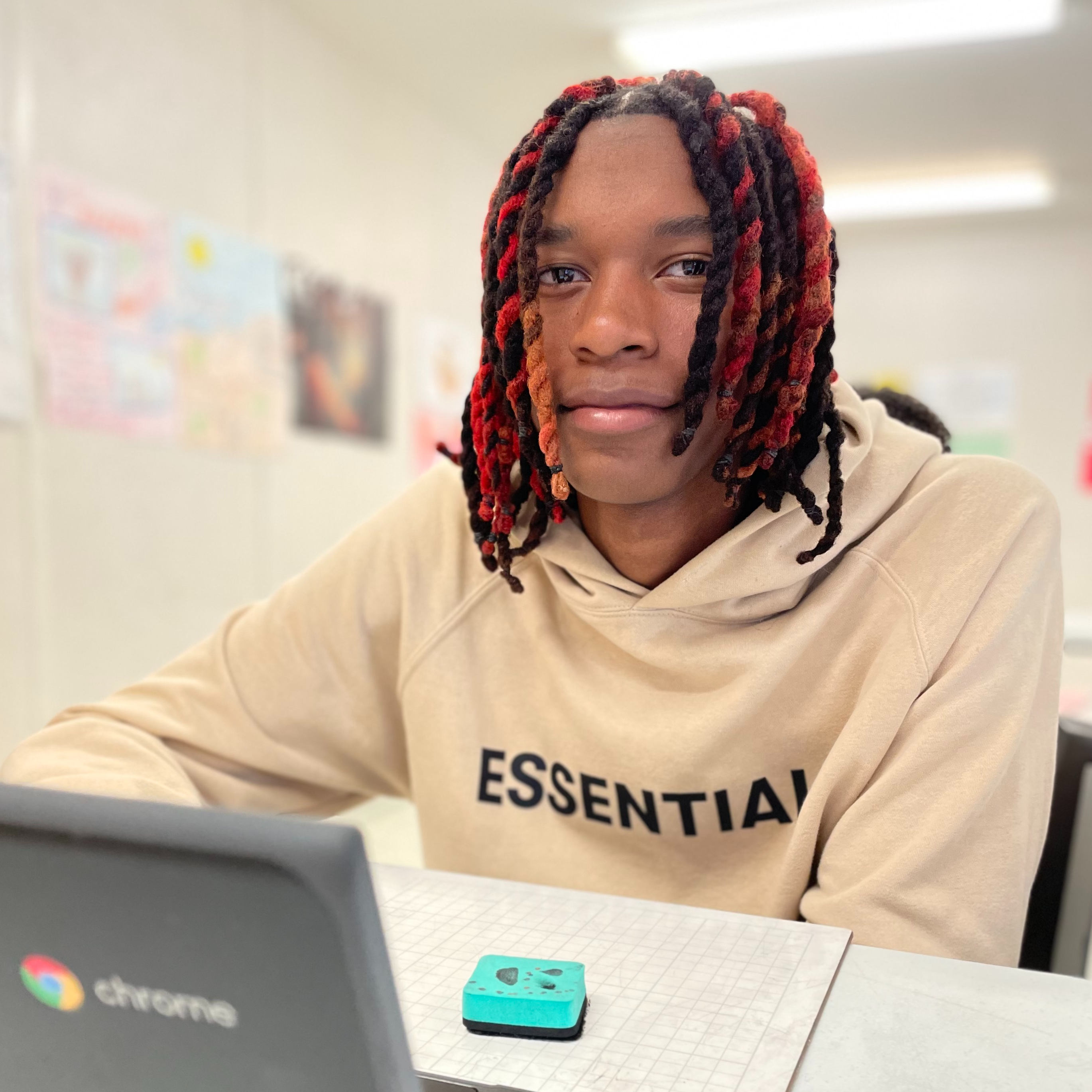 Student sitting at a table working on a laptop and looking at the camera