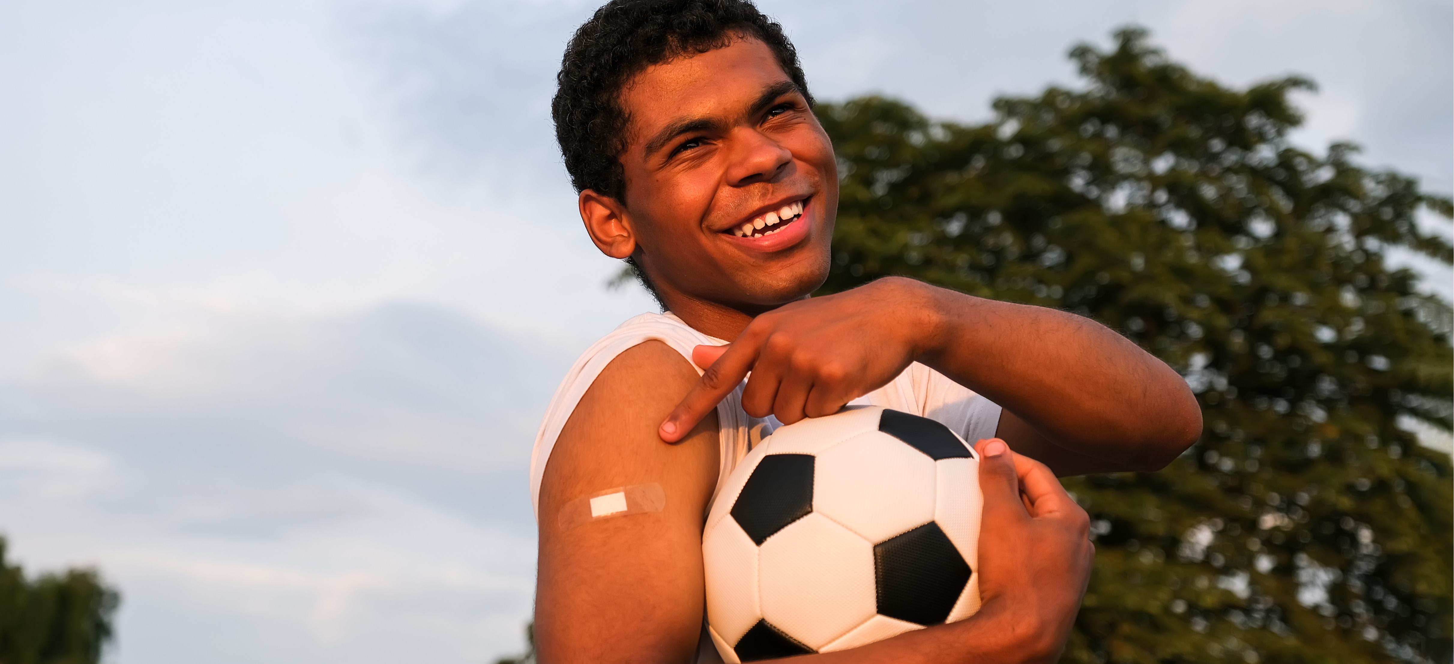 Vaccinated teenage boy smiling holding soccer ball