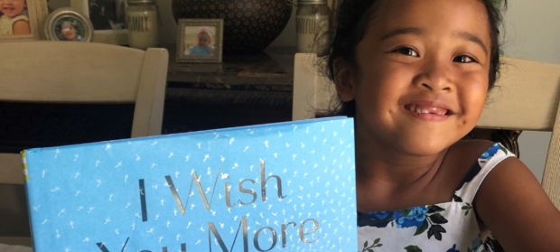 a girl smiling and holding a picture book