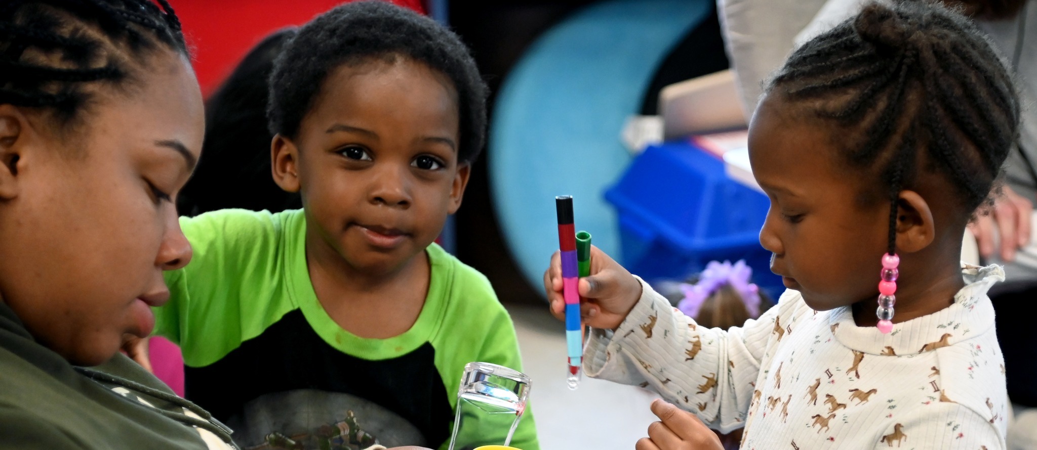 a boy smiling and girl playing with toy 
