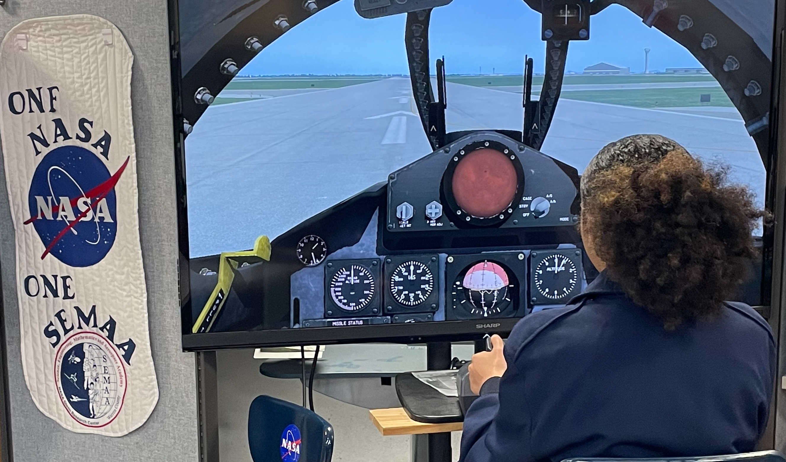 Student in a Space Force JROTC uniform using a flight simulator to learn how to fly a plane