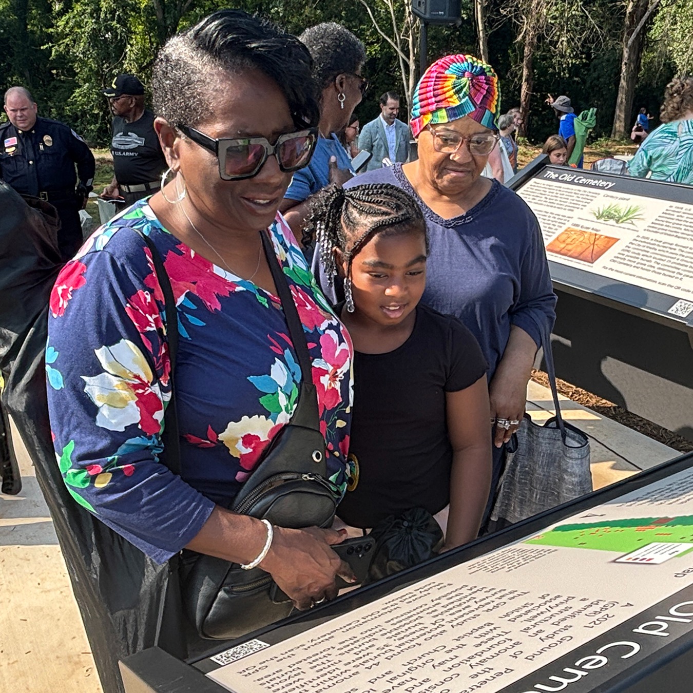 People gathered around the Old Cemetery marker reading the information on the sign
