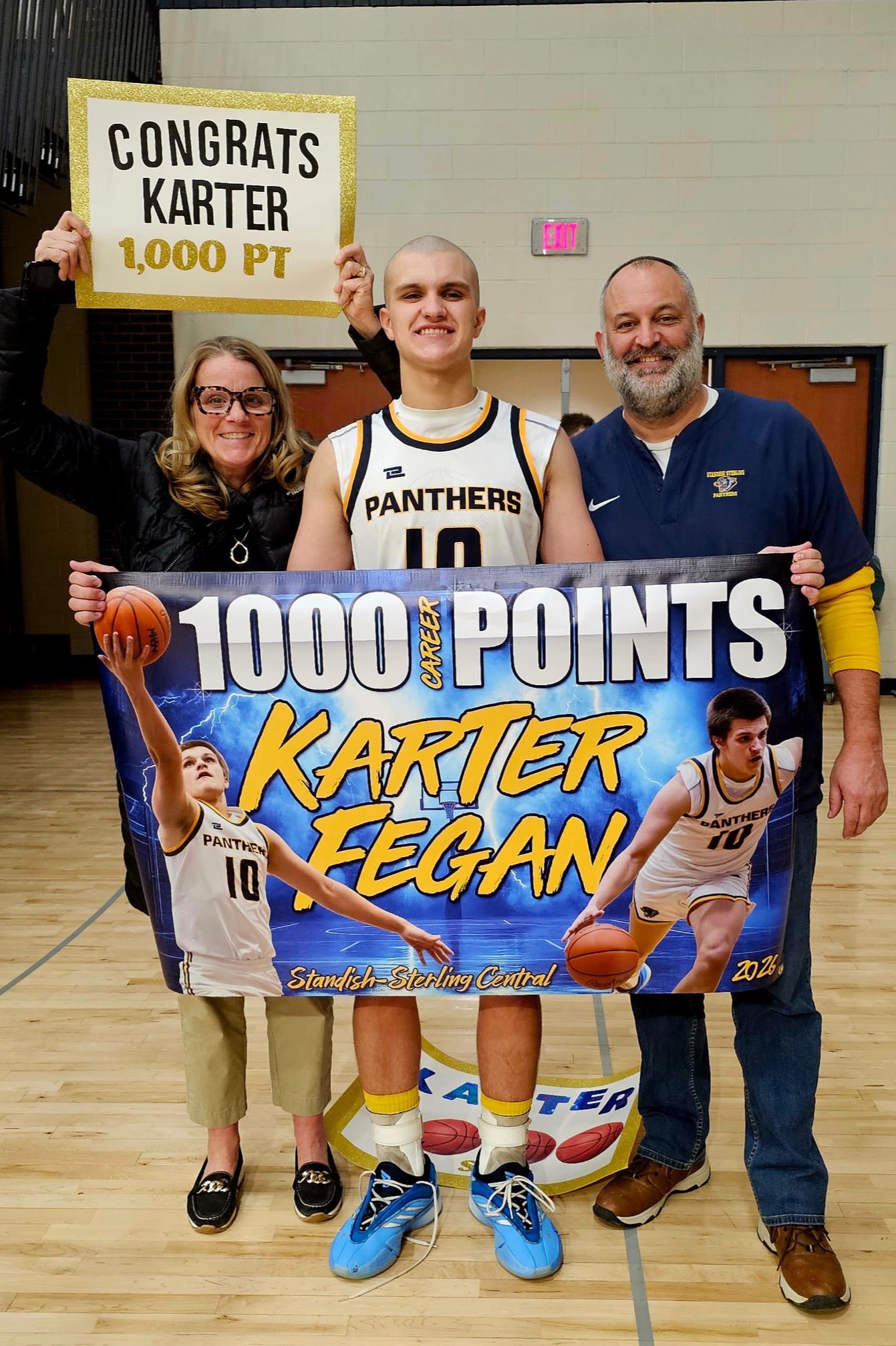 Three people in a gym hold a sign that says '1000 Points' and another that says 'Karter 1000 PT'.