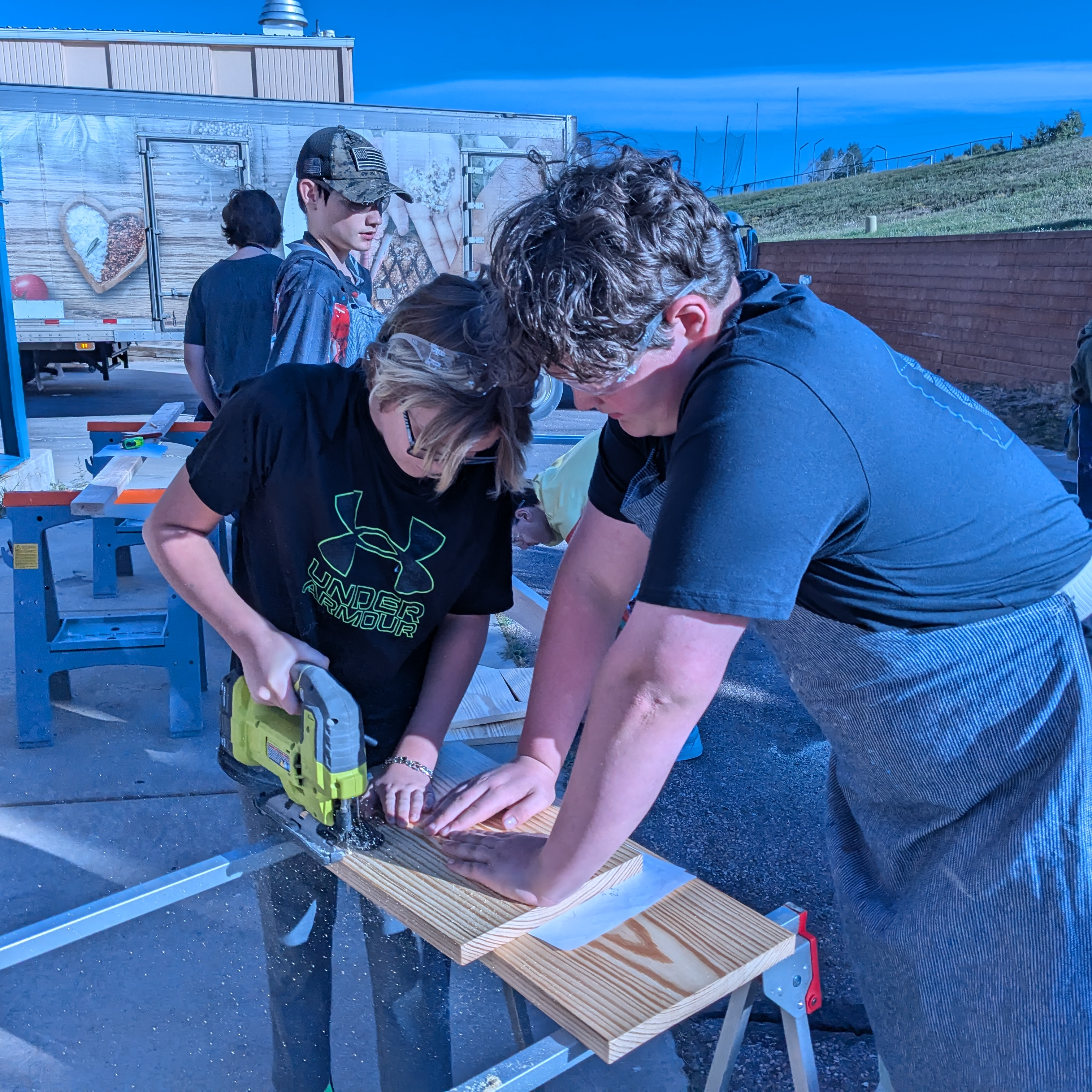 Students cutting a piece of wood in Woodshop class