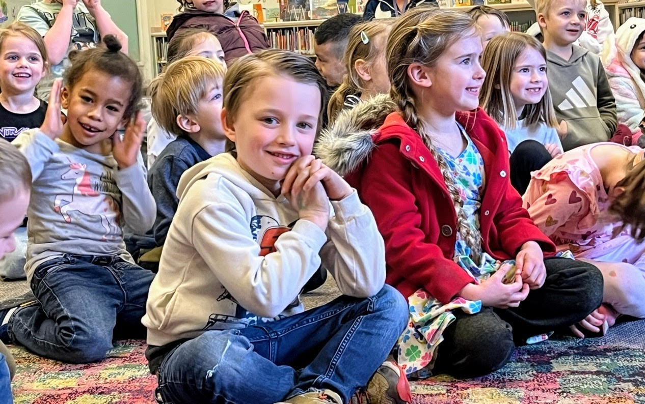 A boy smiling during a magic show in the primary school library.