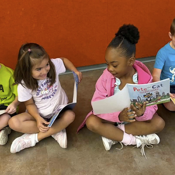 Two girls sit with books on the floor