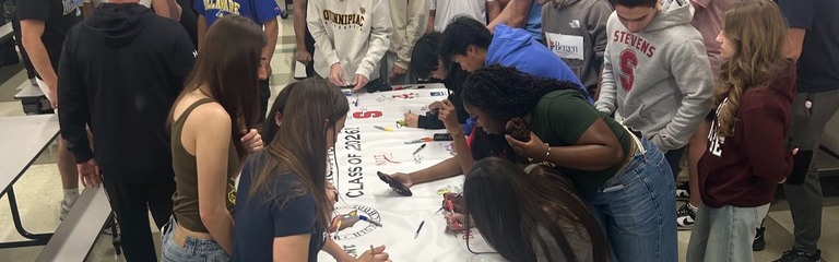 Students writing on a banner for senior decision day
