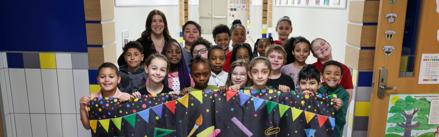 Students posing in the new Edison building and holding a "Welcome Back" banner. 