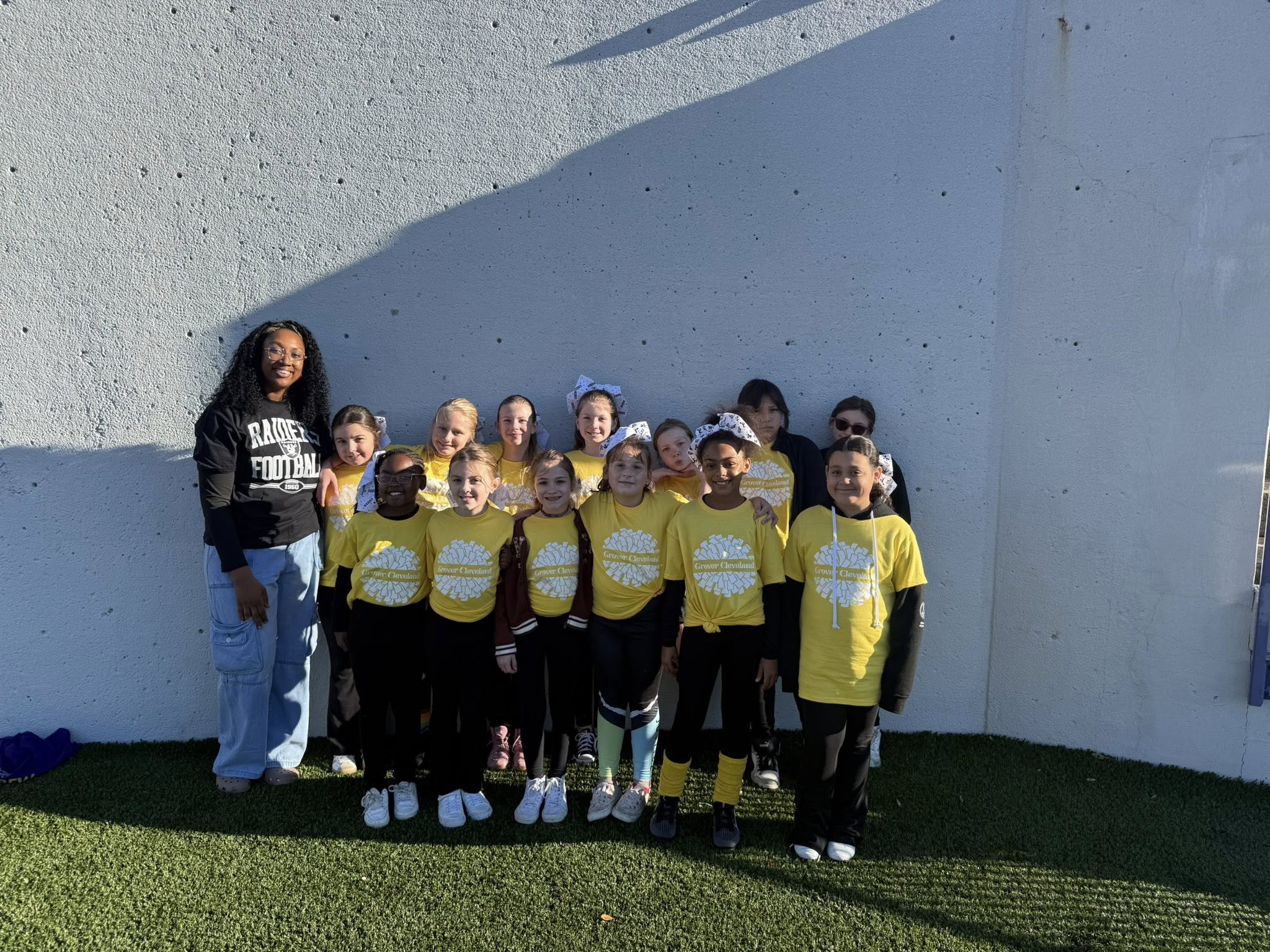 Young girls standing in yellow shirts and smiling. 