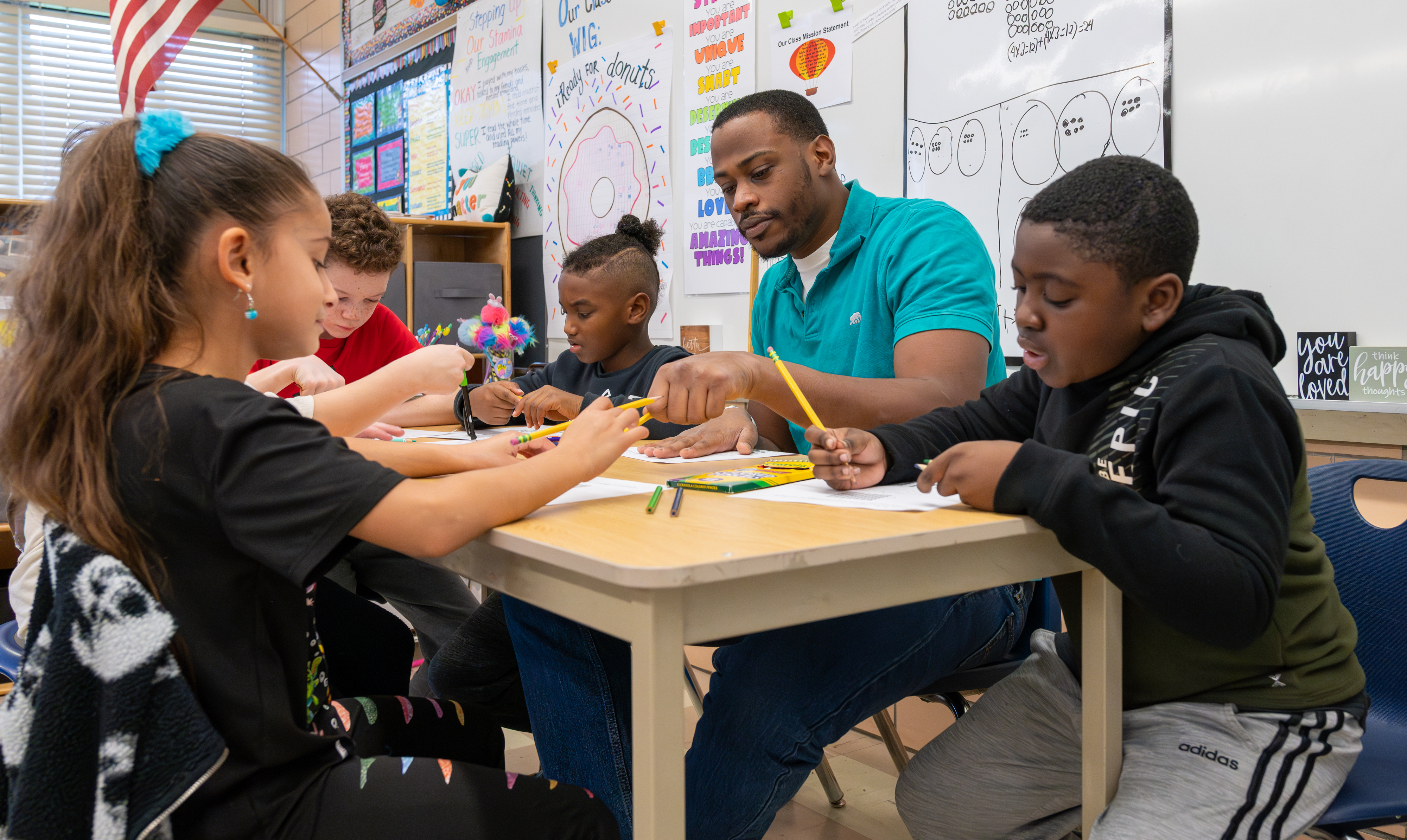 Male teacher working with students at desk