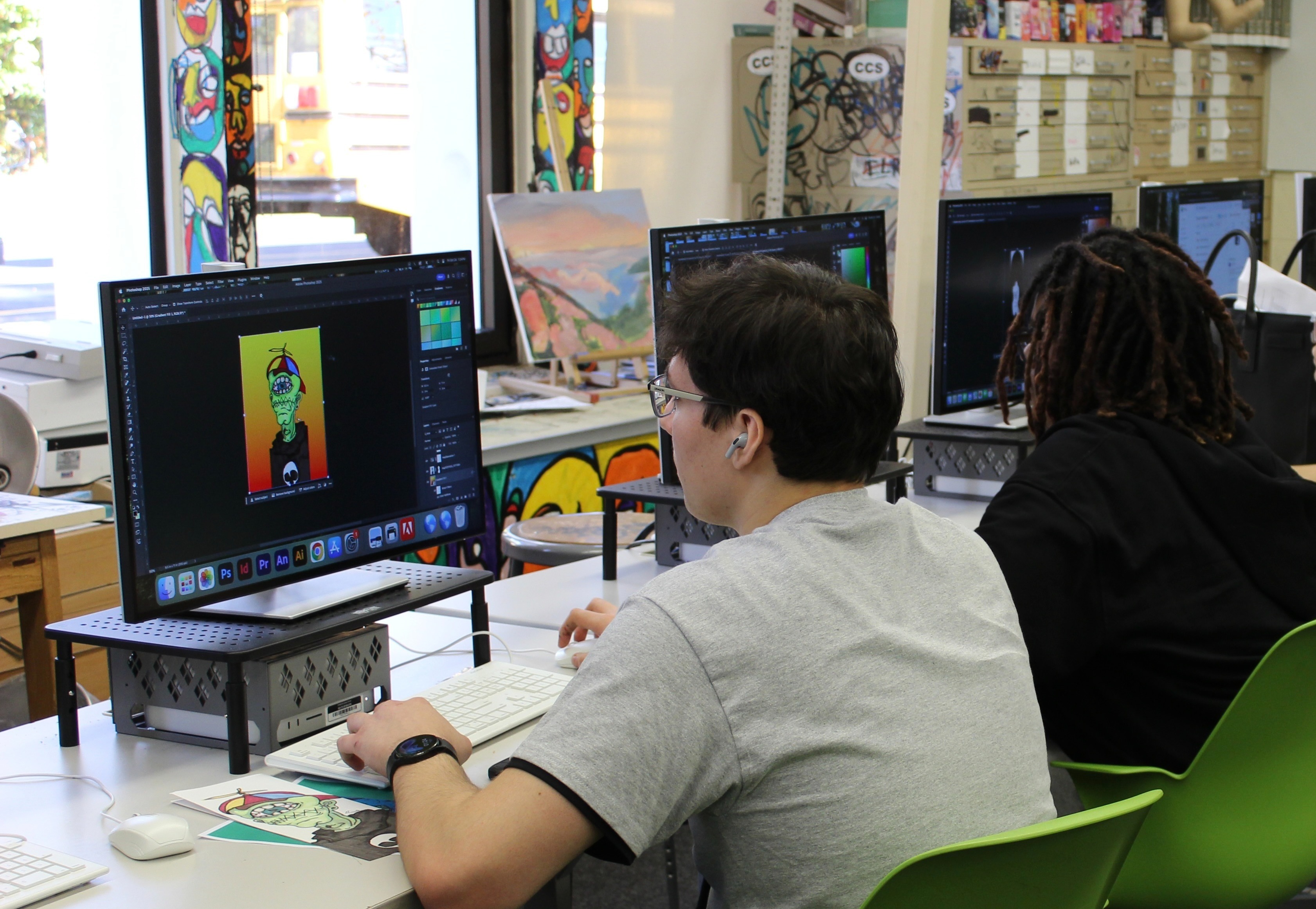 teacher assists a row of students working at computer stations