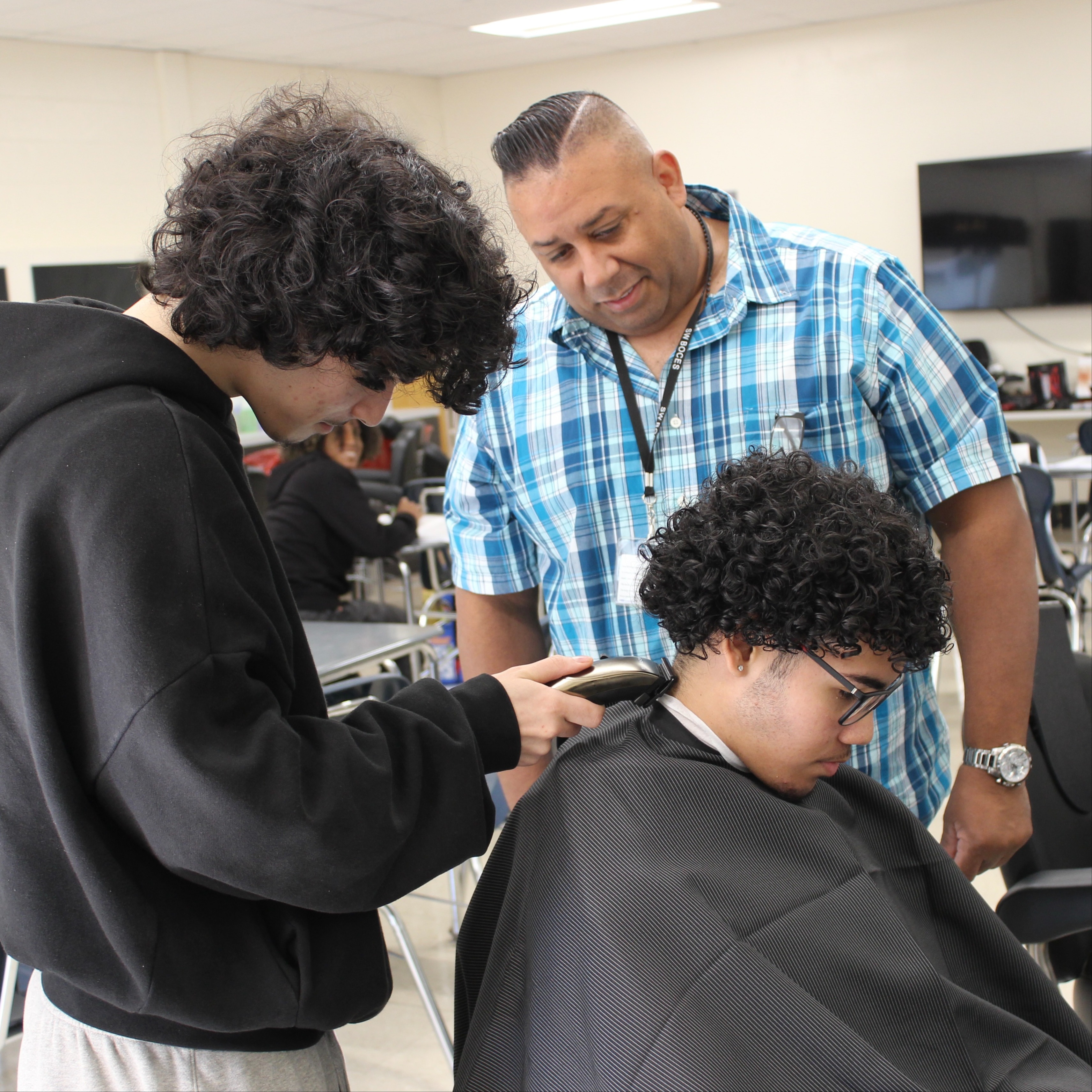 Instructor observes as Barbering student practices technique on a client