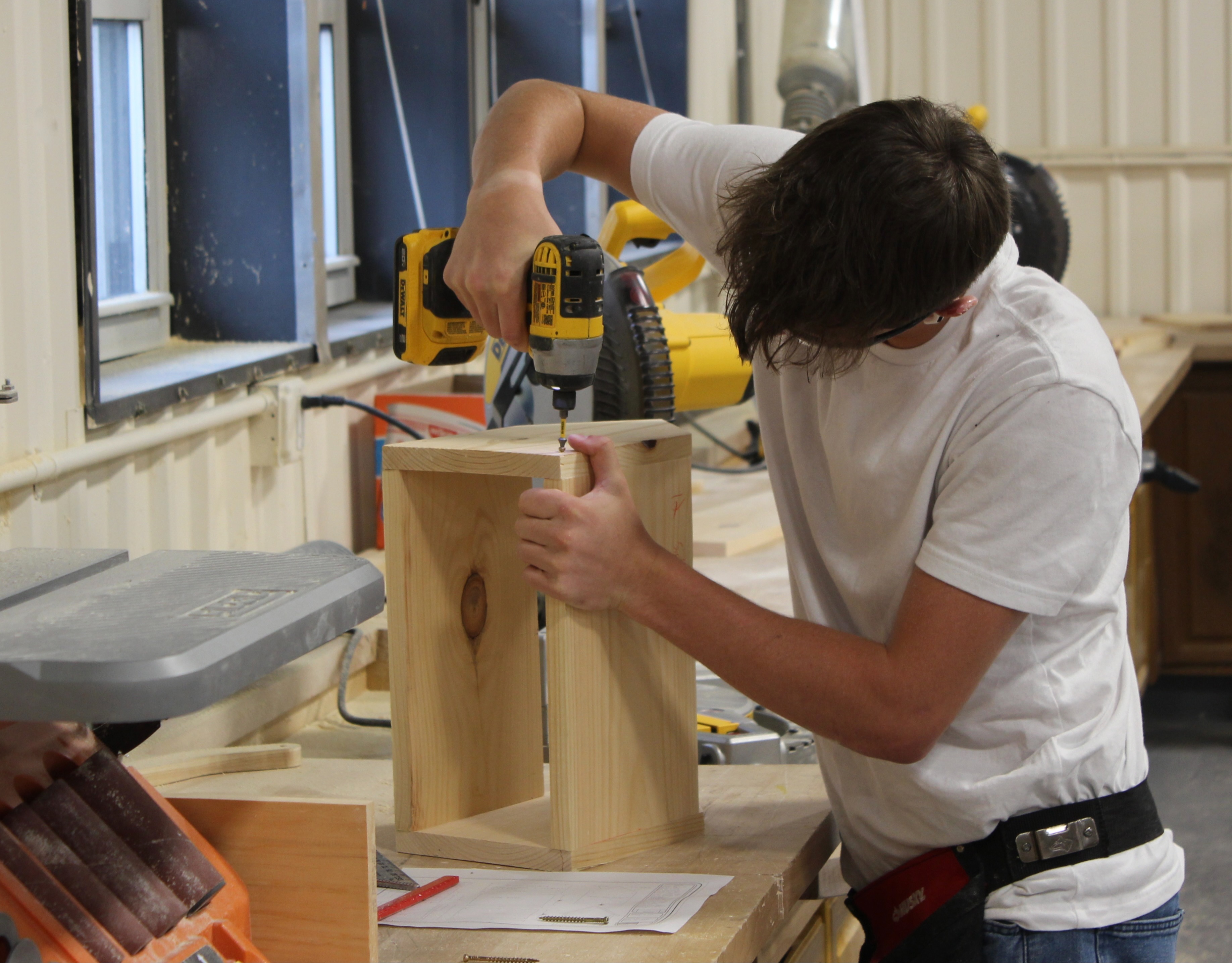 carpentry students drills into a block of wood for a class project