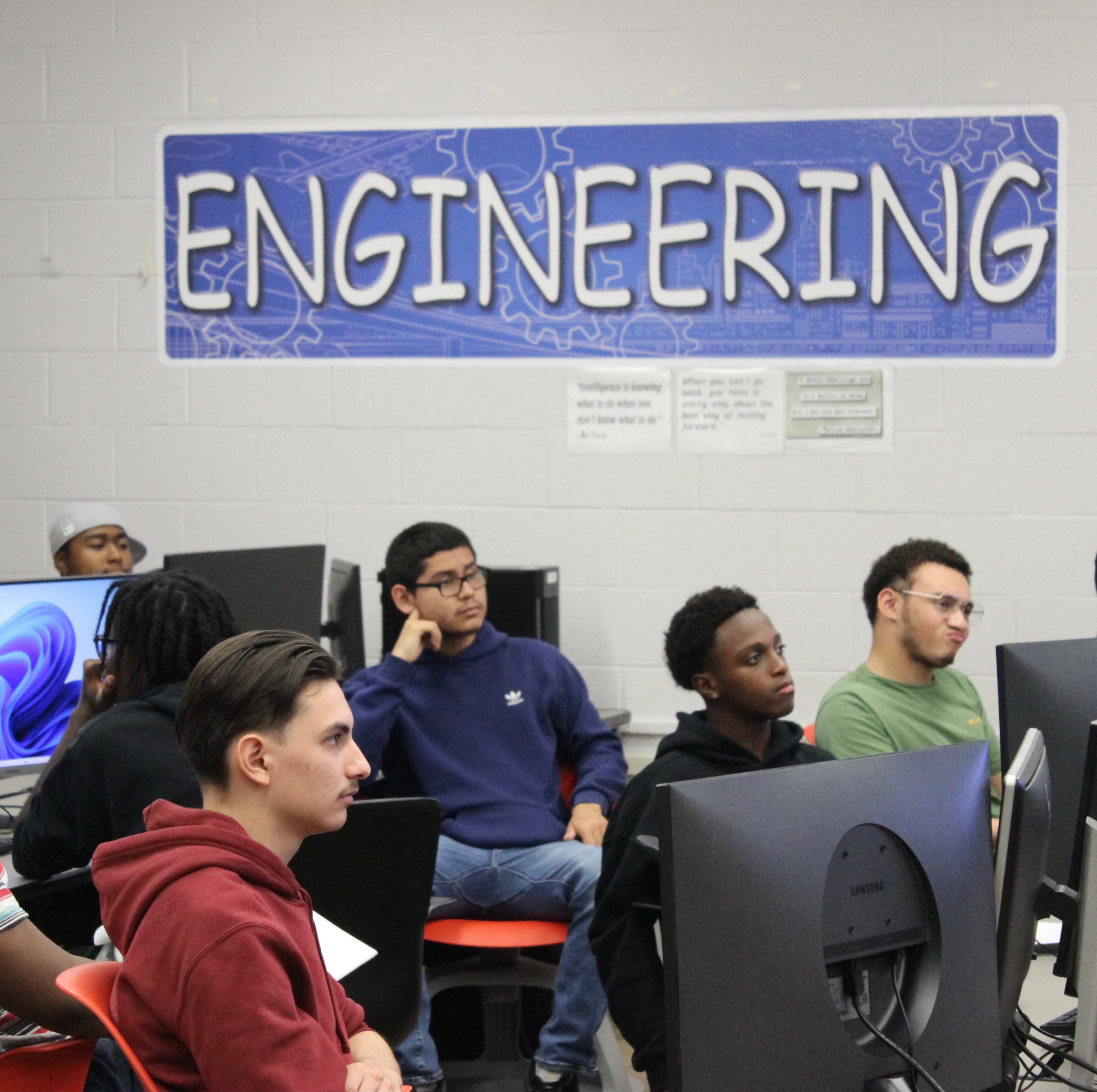 pre-engineering students at workstations look on as teacher lectures