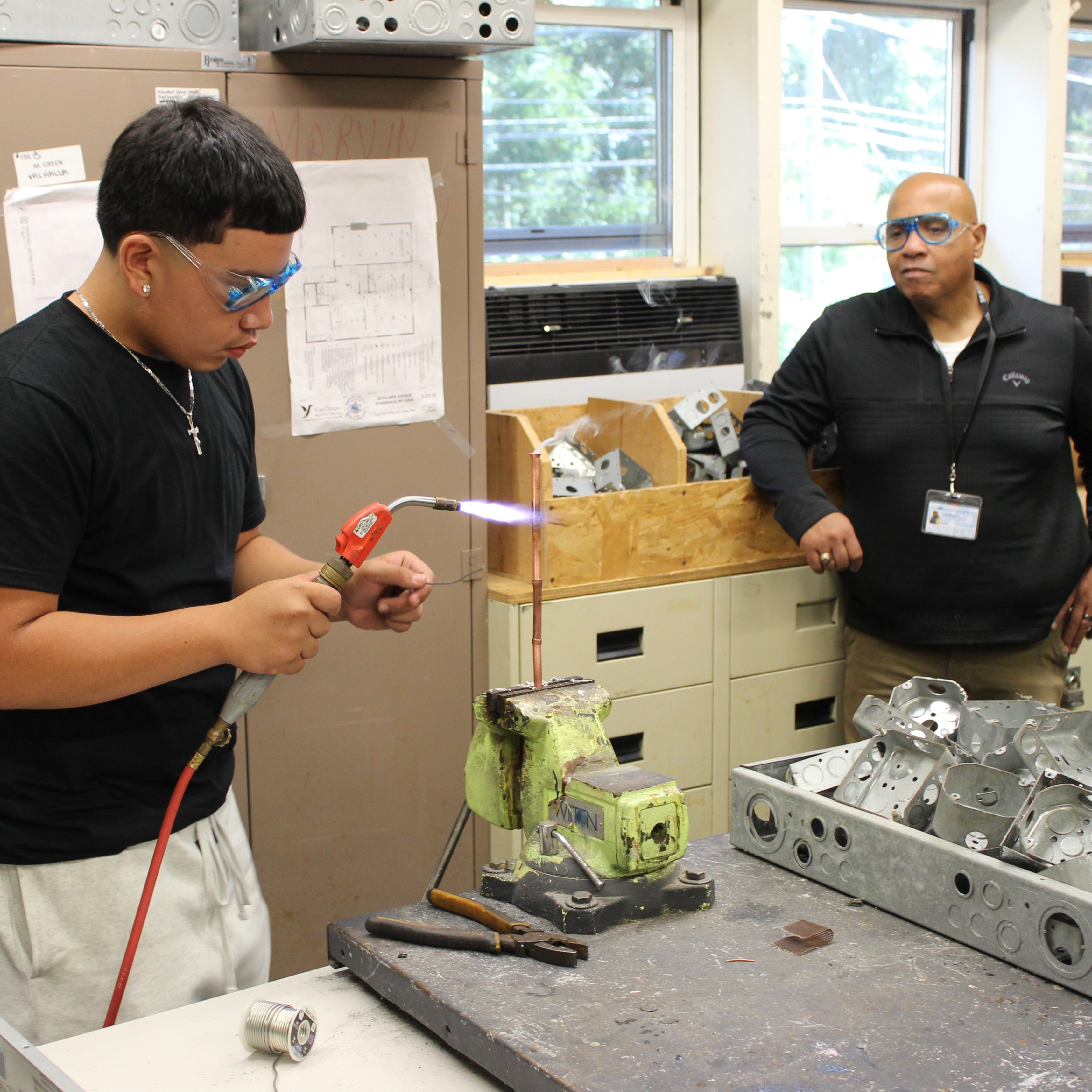 HVAC student solders while instructor observes
