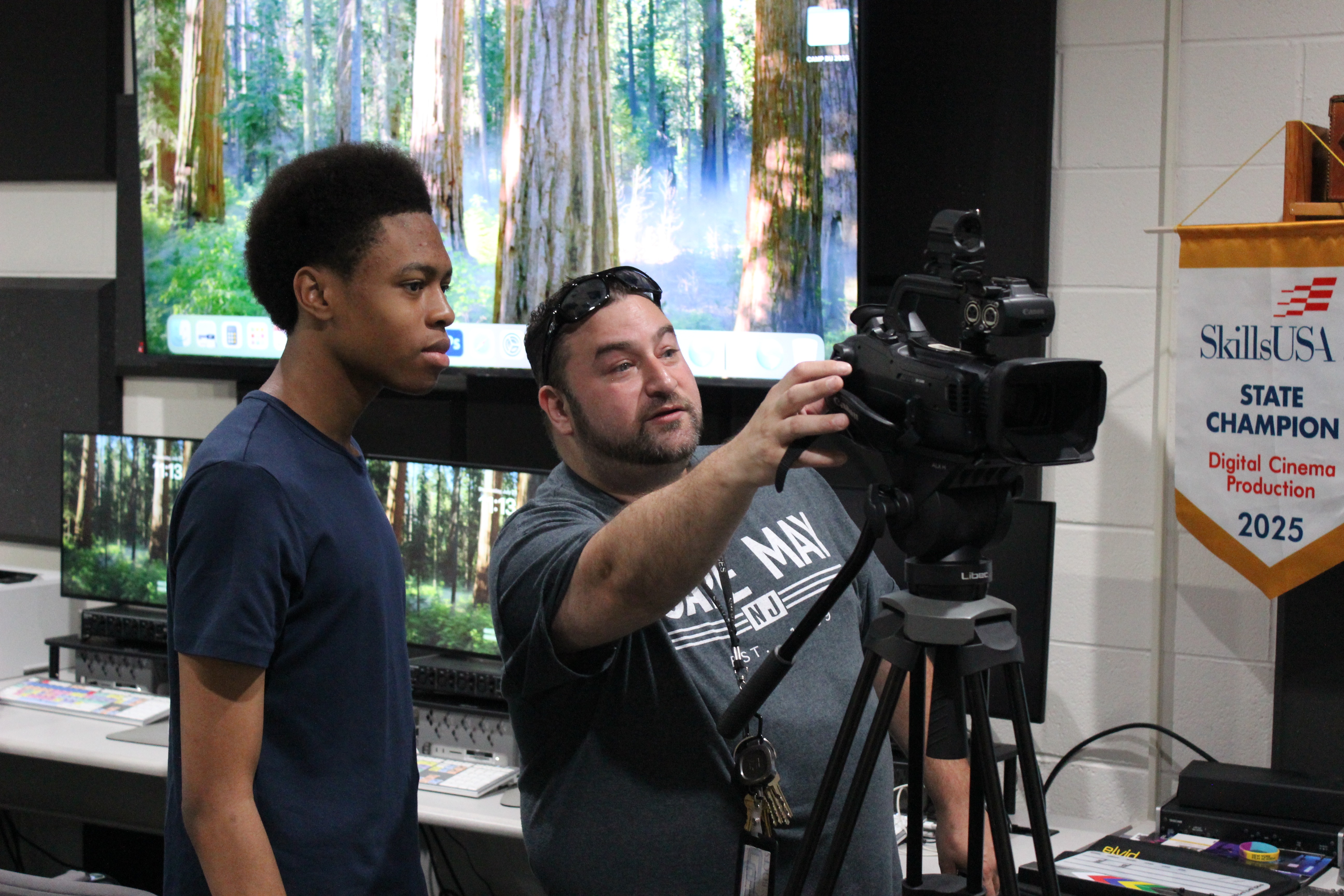 Video Production Teacher shows students camera skills in studio
