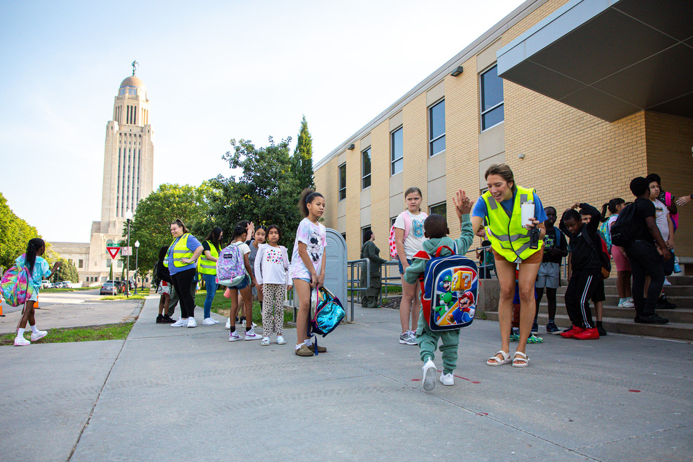 Staff greet elementary students at McPhee with the state capitol building in the background.