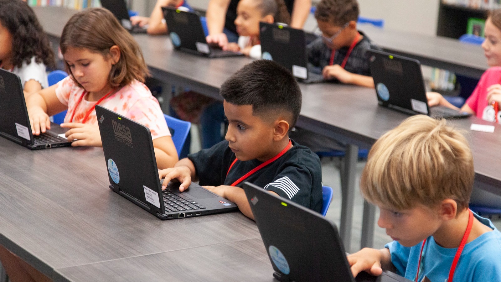 Students working at tables with laptops