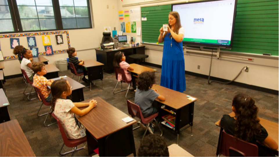 teacher standing in front of a class hold a flashcard