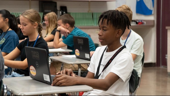 students sitting at desks working on laptops