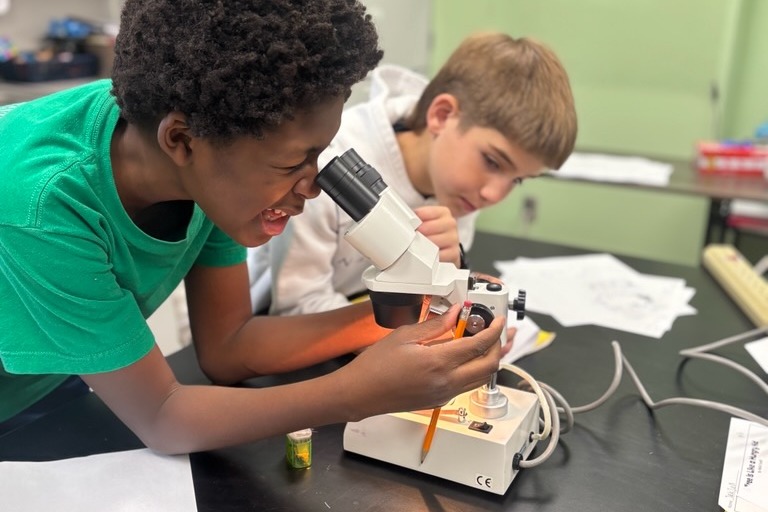 2 students looking through microscope