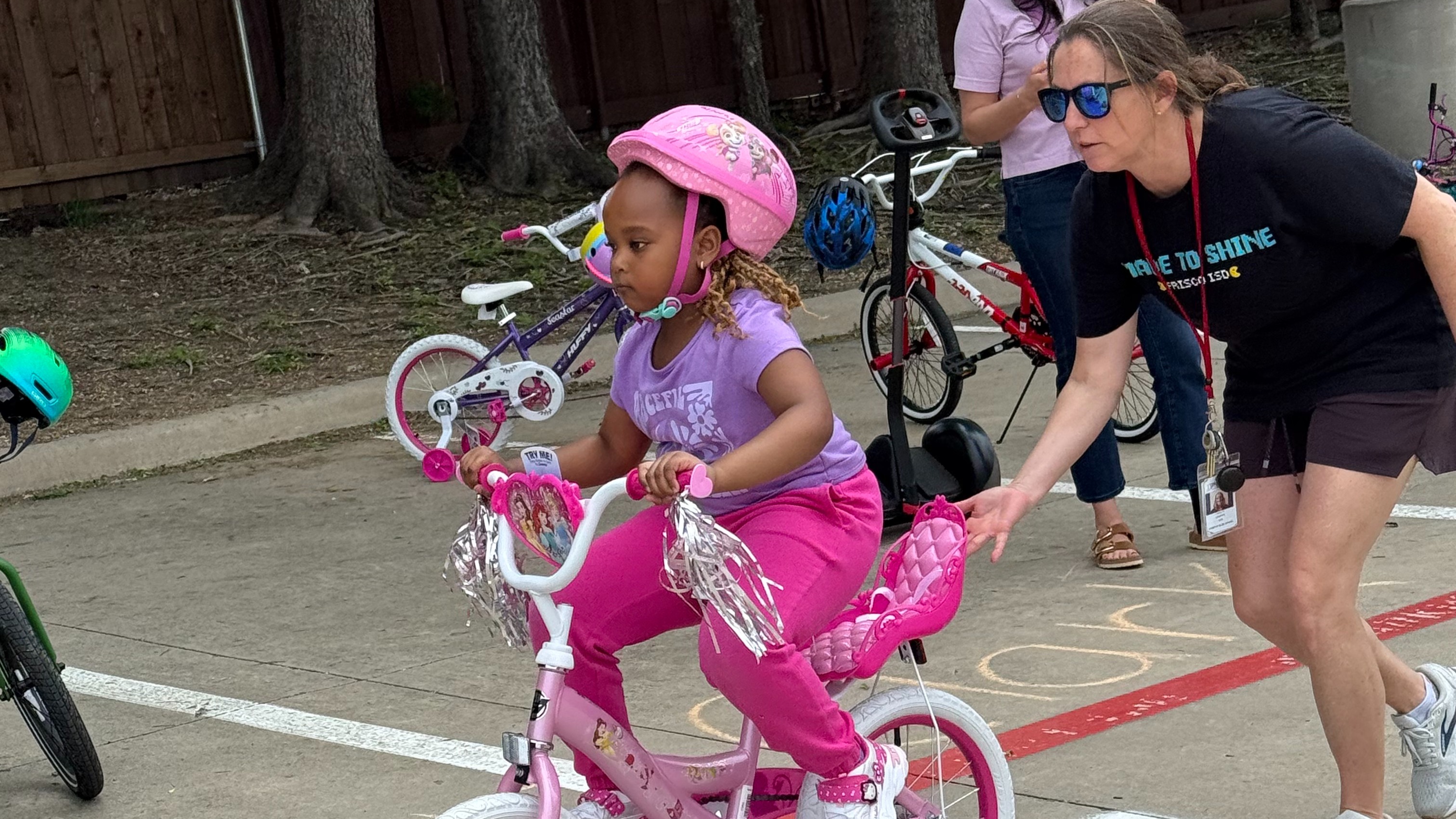 Teacher helping student on bike.