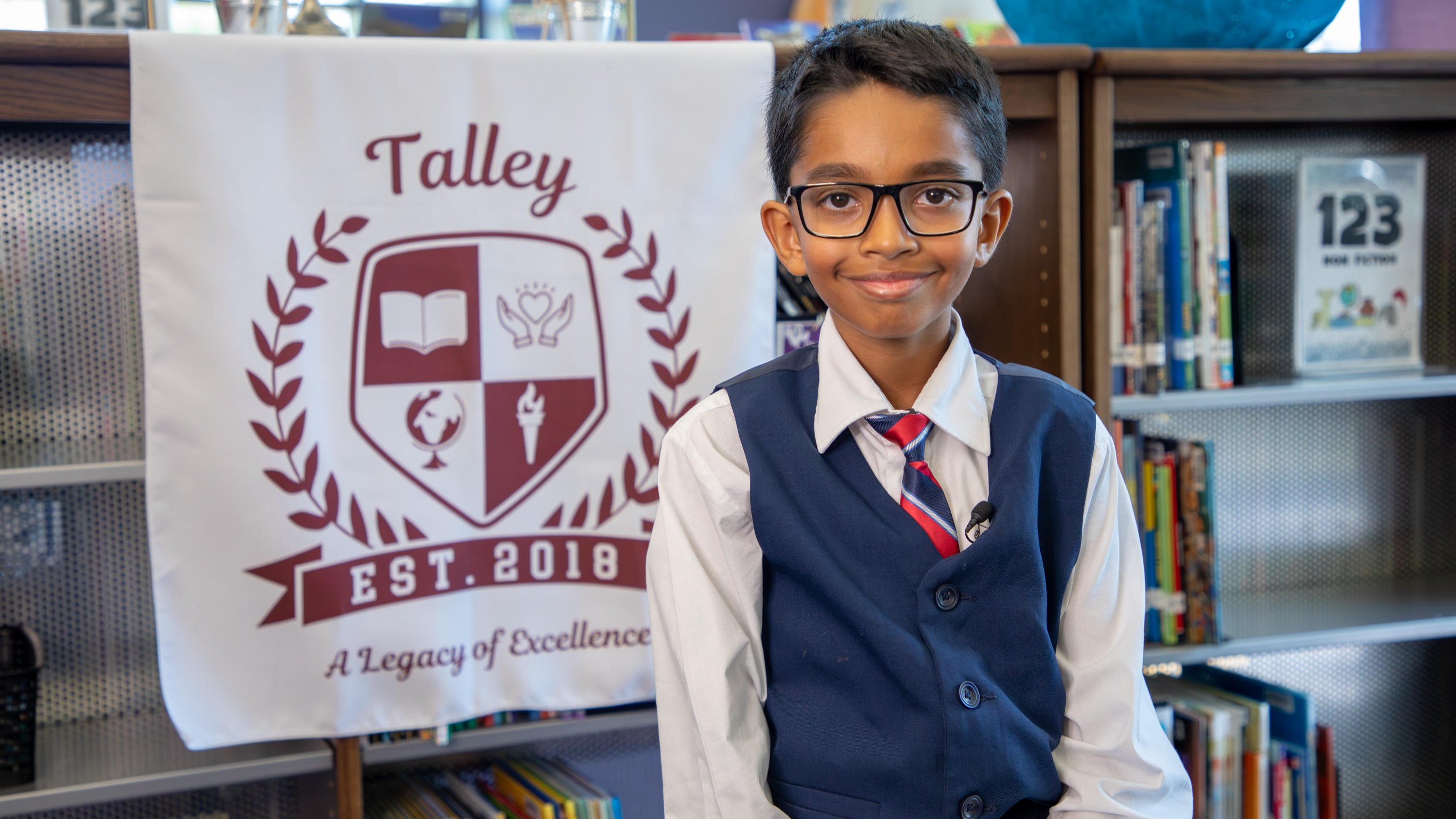 A boy smiling in front of the Talley Crest.