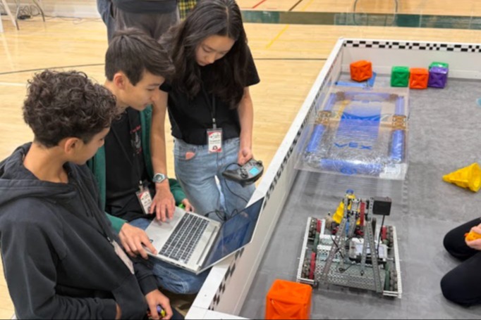 three students in front of a lap top an robot