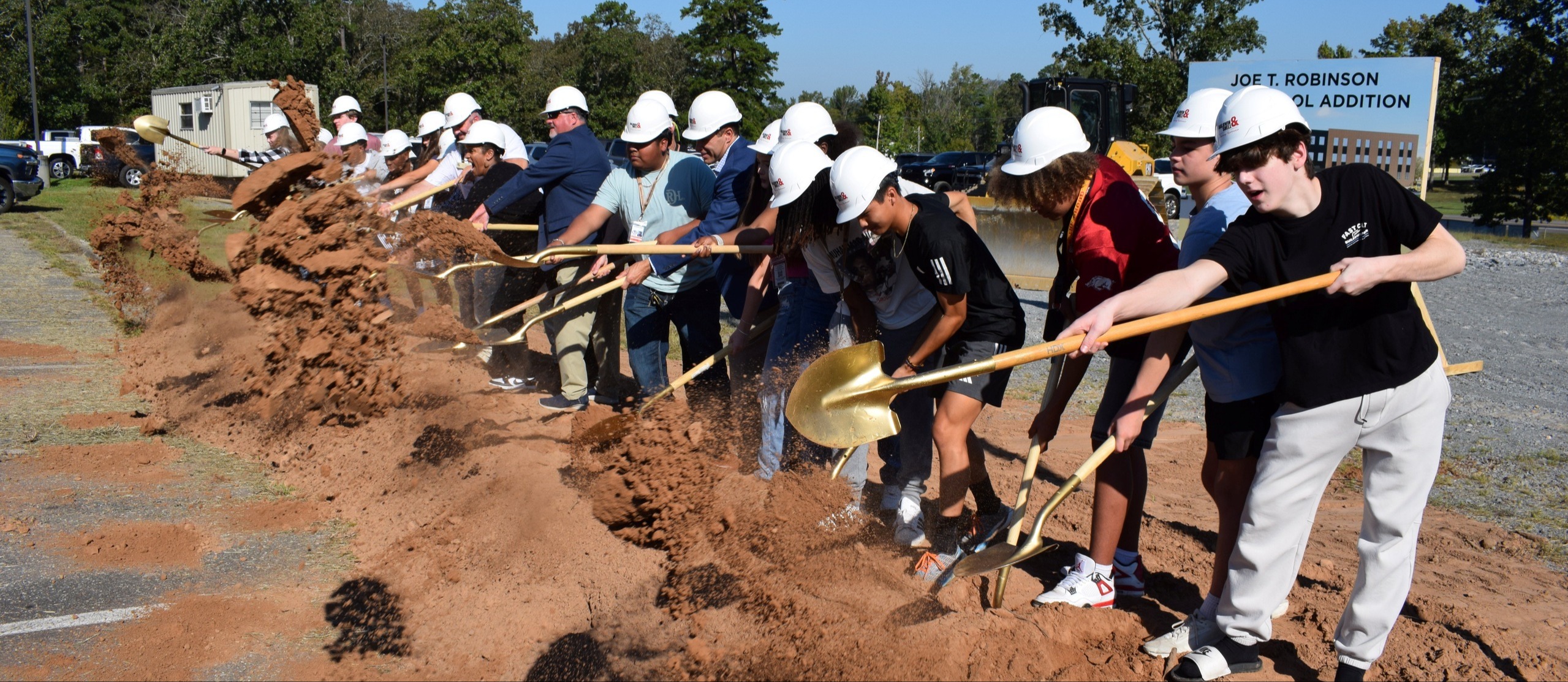 line of people turning shovels at a groundbreaking