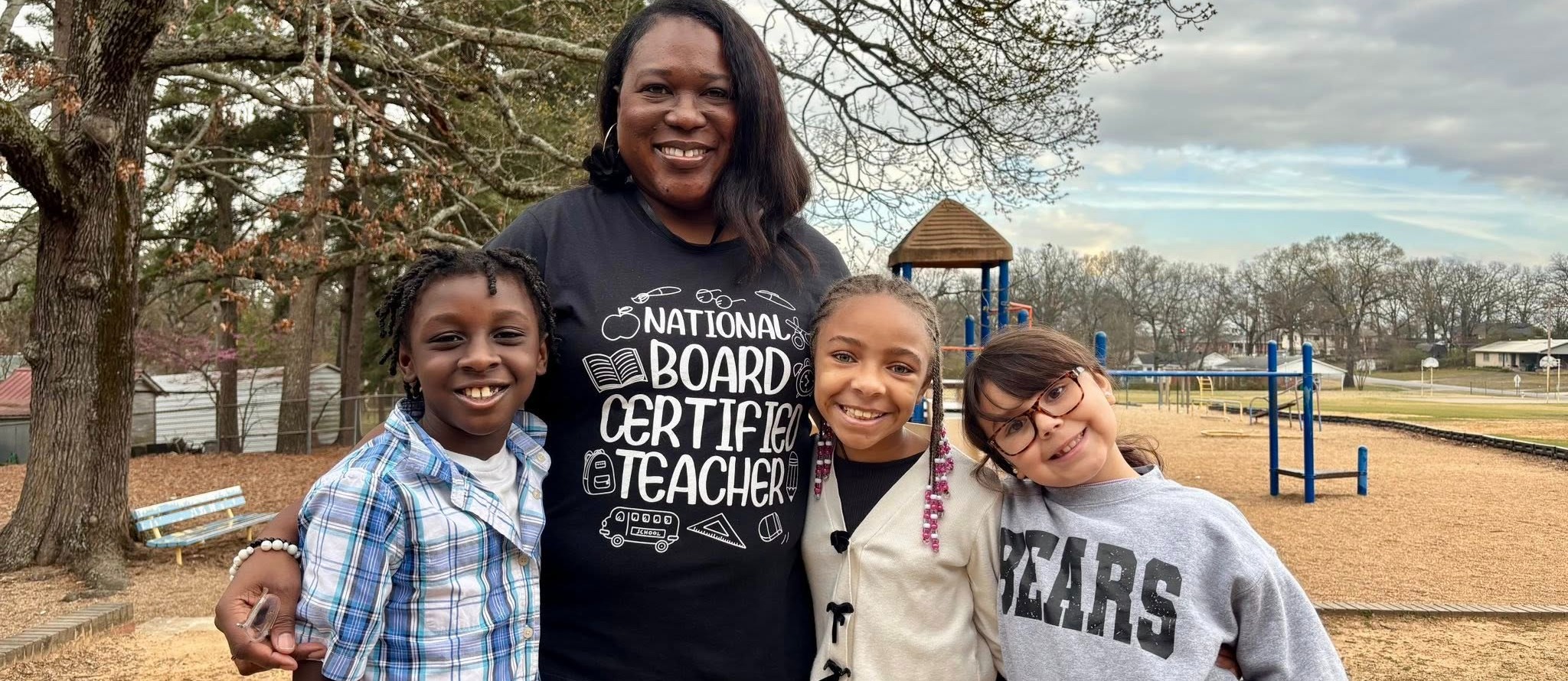 PCSSD MAR Slider of a national board certified teacher and three students. They are outside in front of the playground.