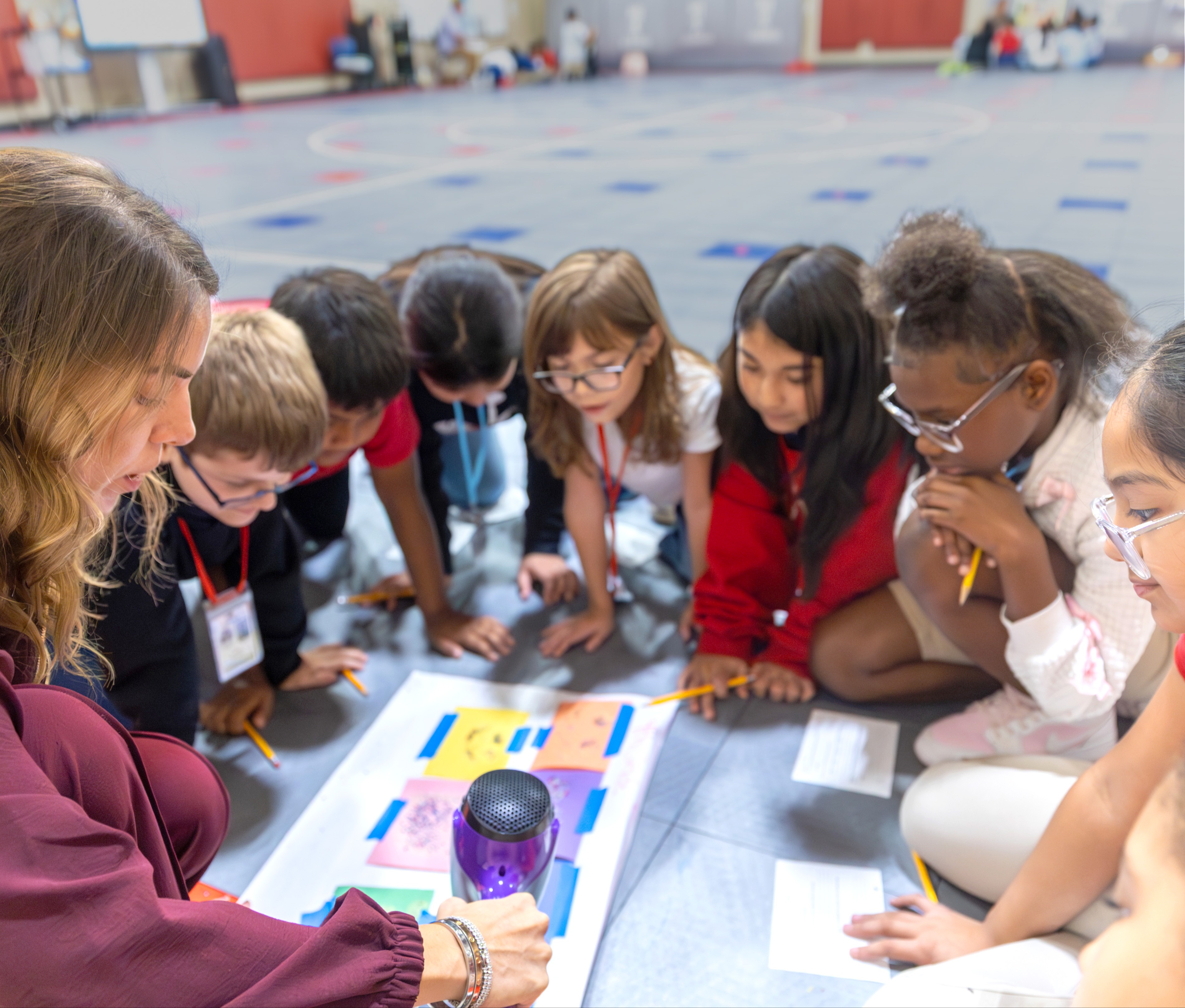 Group of students and a teacher sitting on the floor working on a project
