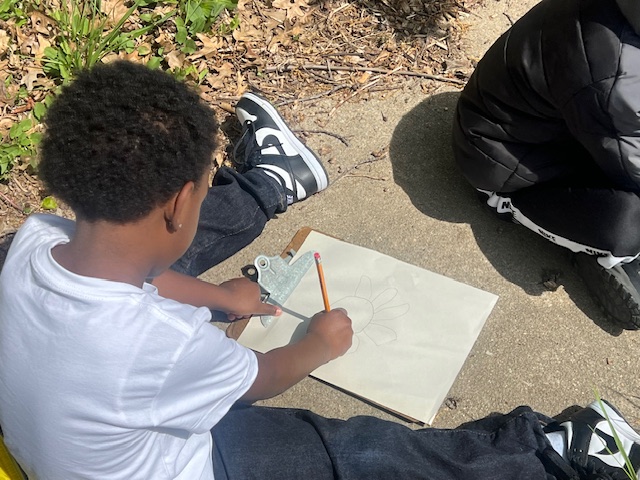 Preschool student writing with pencil outside