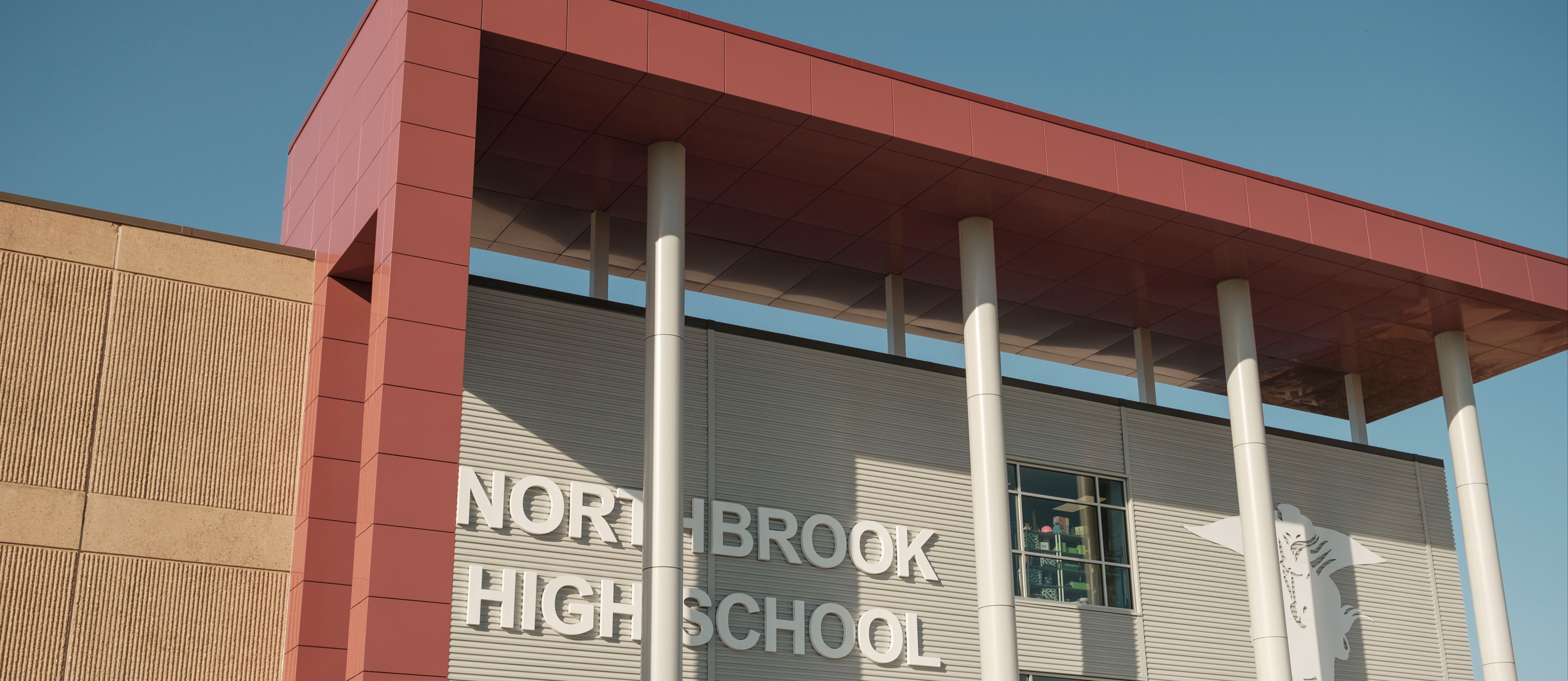 A school building with a red overhang. White text reads "NORTHBROOK HIGH SCHOOL".