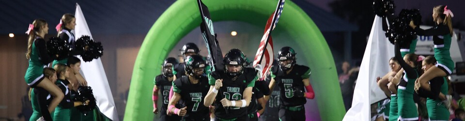 High School football team running through tunnel.