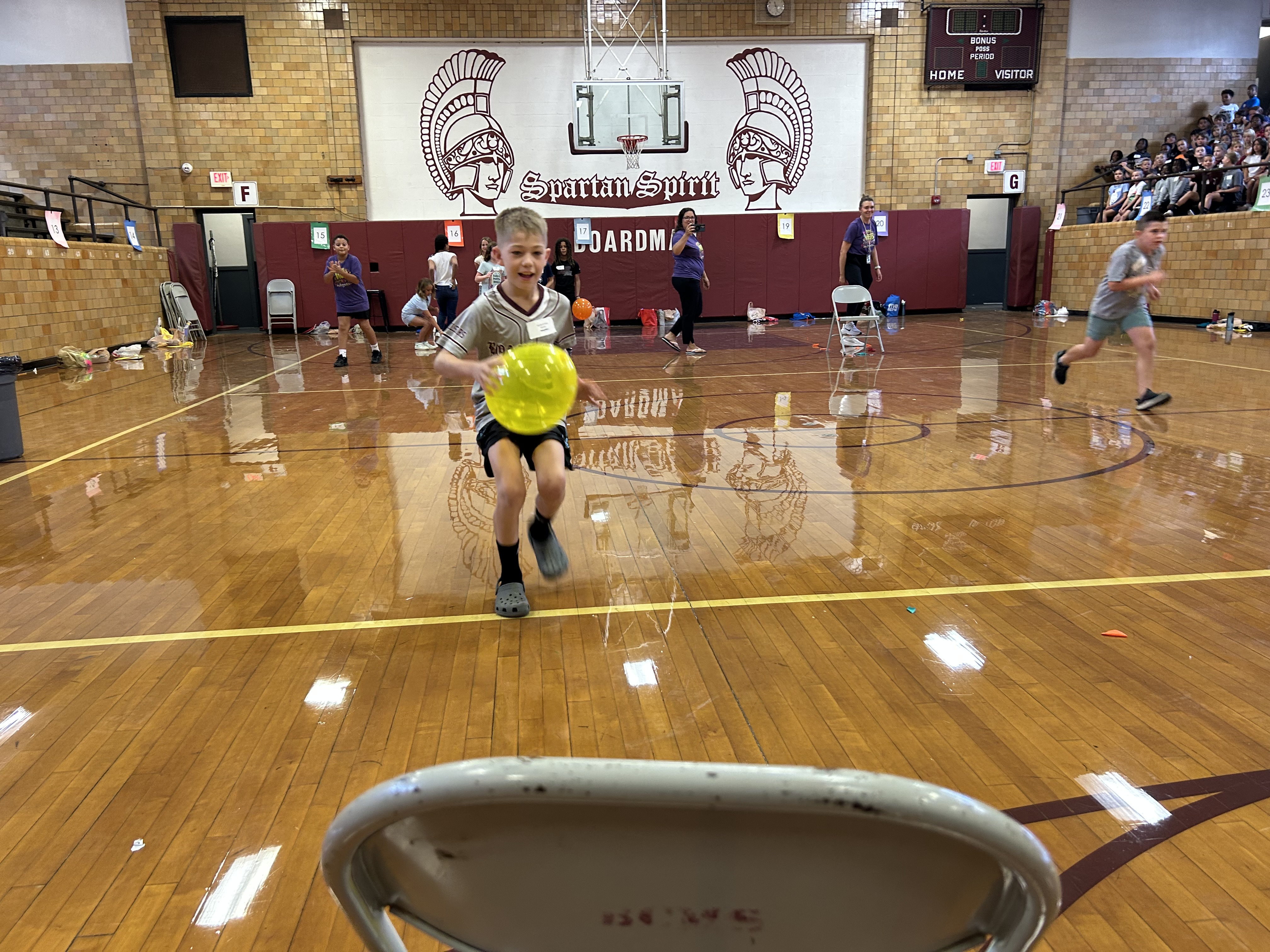 boy holding a balloon in a relay race across BCIS gym floor