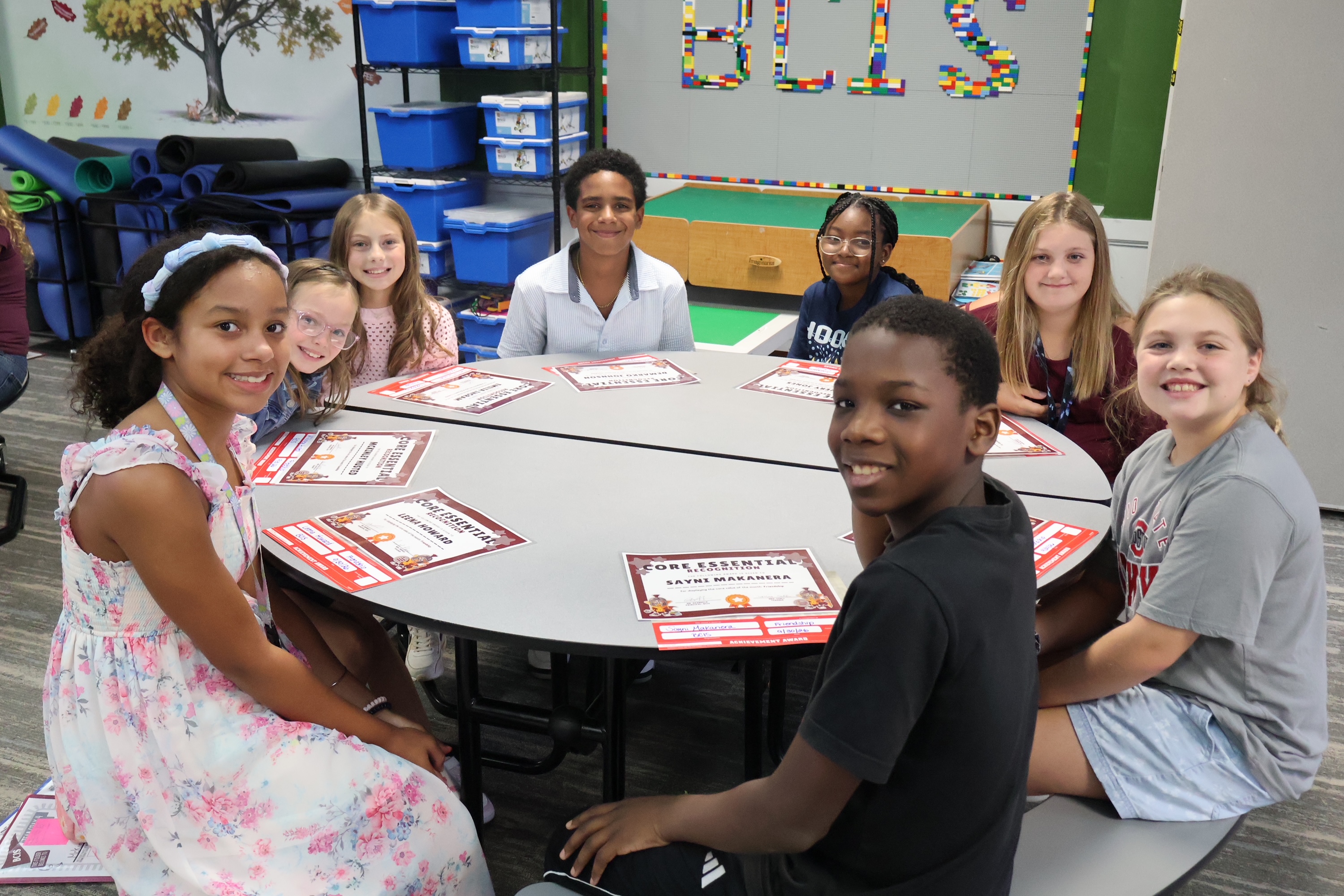 8 students sitting around a table with certificates for core essentials