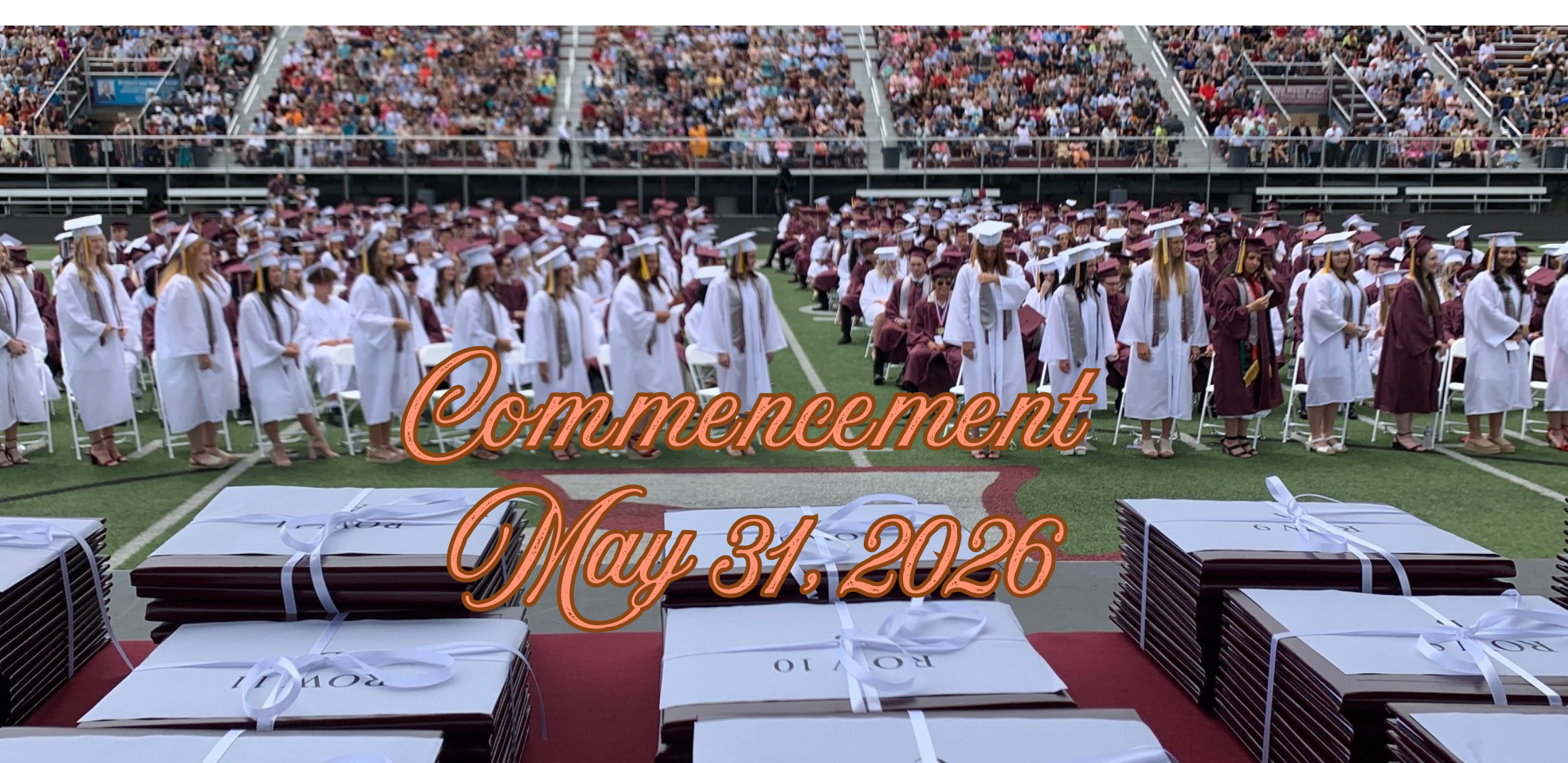 Graduates on the Stadium Field with diplomas in front Commencement May 31, 2026